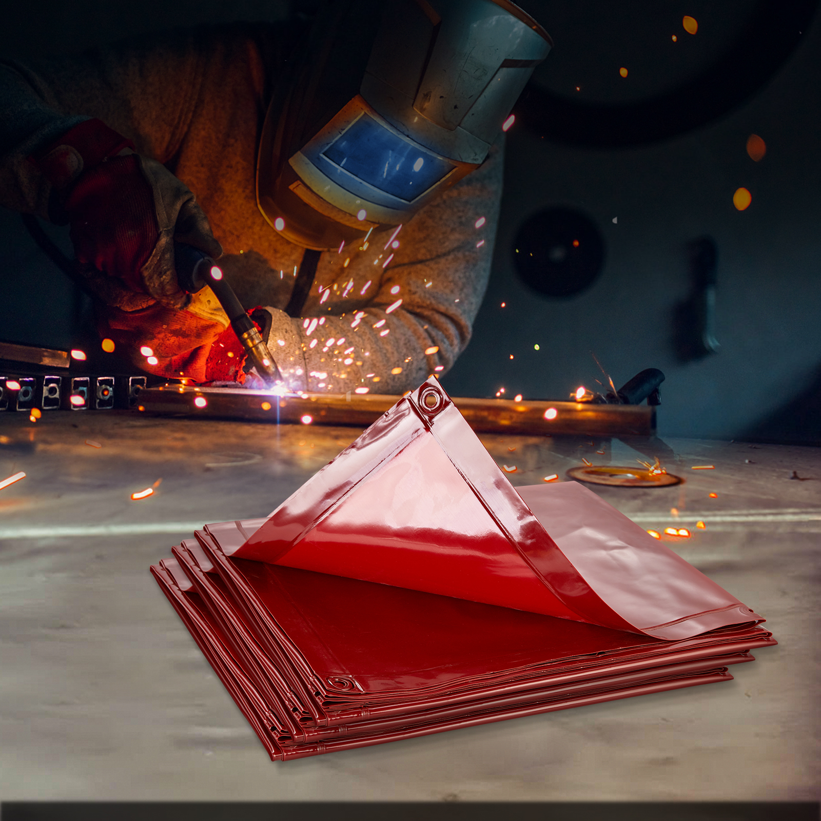 Una pila de lonas rojas y brillantes en primer plano con un soldador trabajando al fondo.