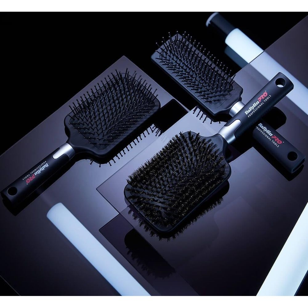 Tre spazzole per capelli nere BabylissPro sono disposte su una superficie lucida e illuminata.