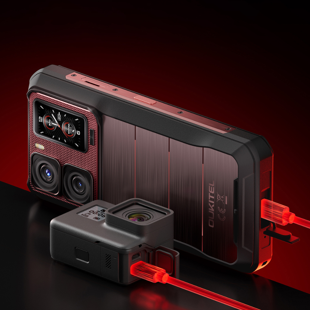 Wytrzymały smartfon Oukitel i kamera sportowa na ciemnej powierzchni z czerwonymi kablami ładującymi.
