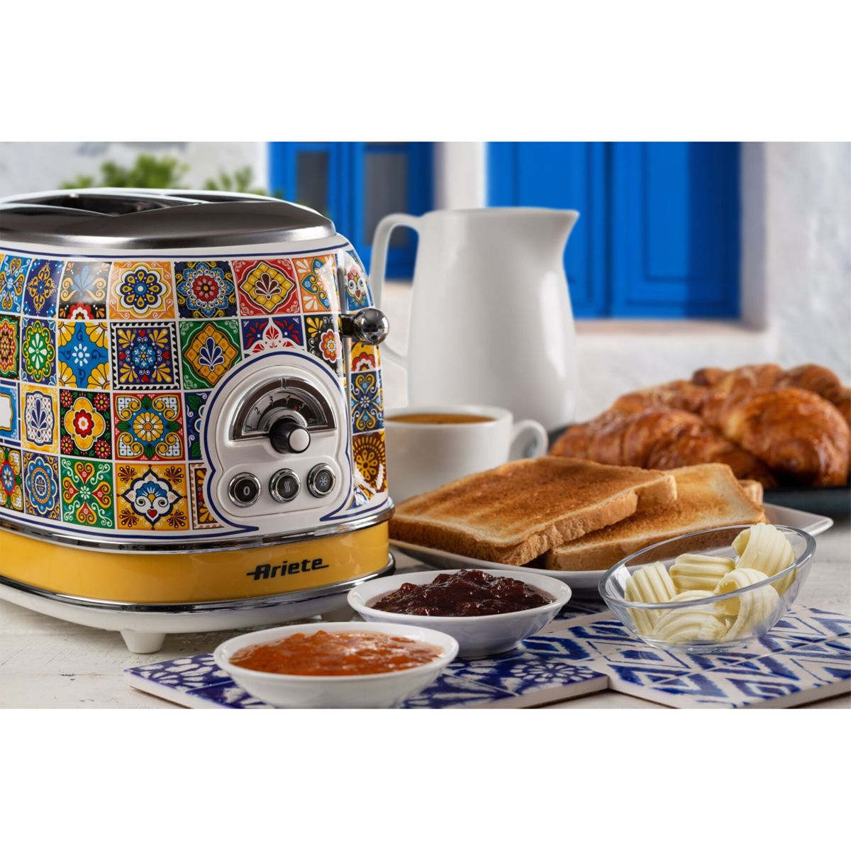 Tapeto colorato con motivi mediterranei su un tavolo da colazione con toast, burro e marmellata.
