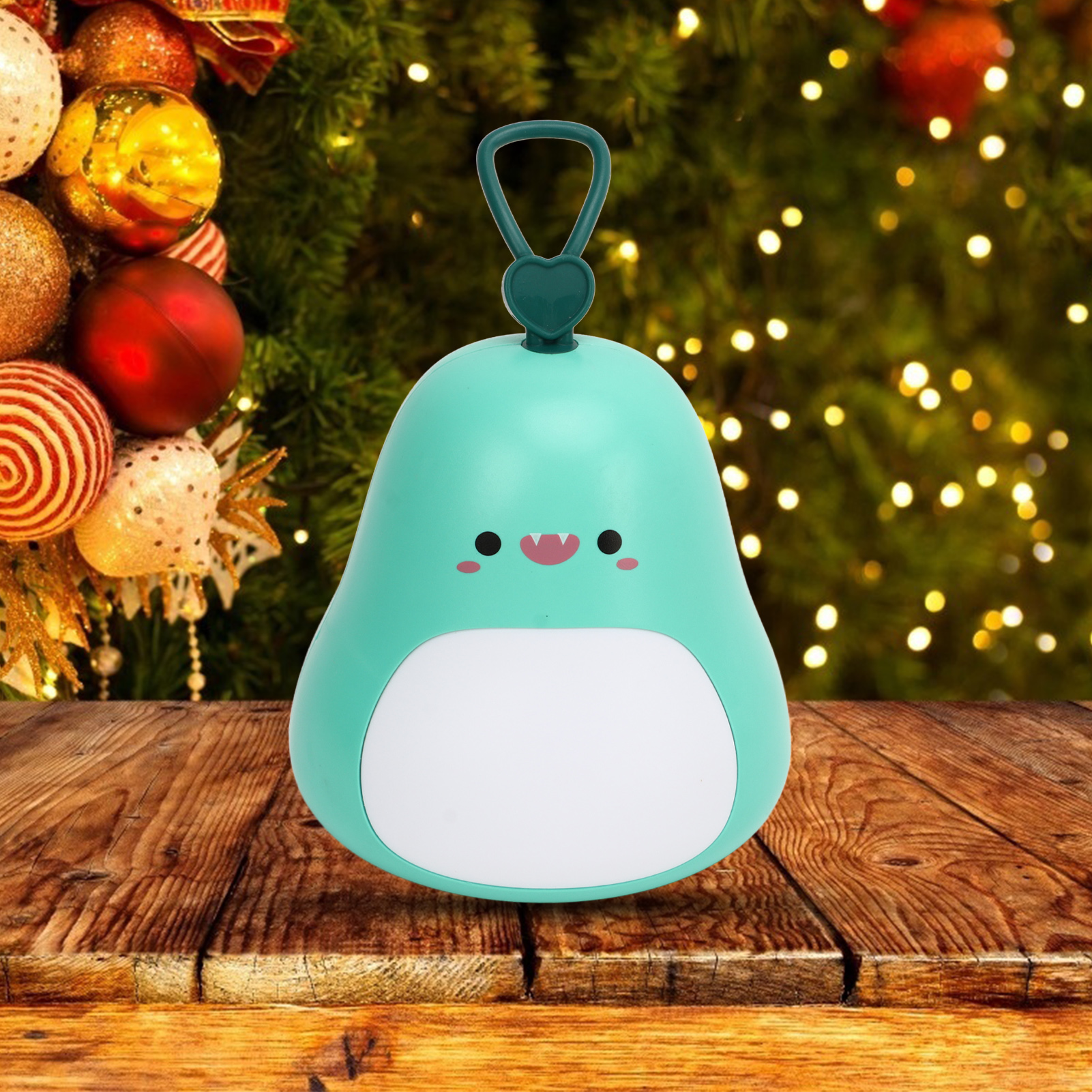 Eine süße türkise Dinosaurier-Lampe auf einem Holztisch vor einem Weihnachtsbaum.