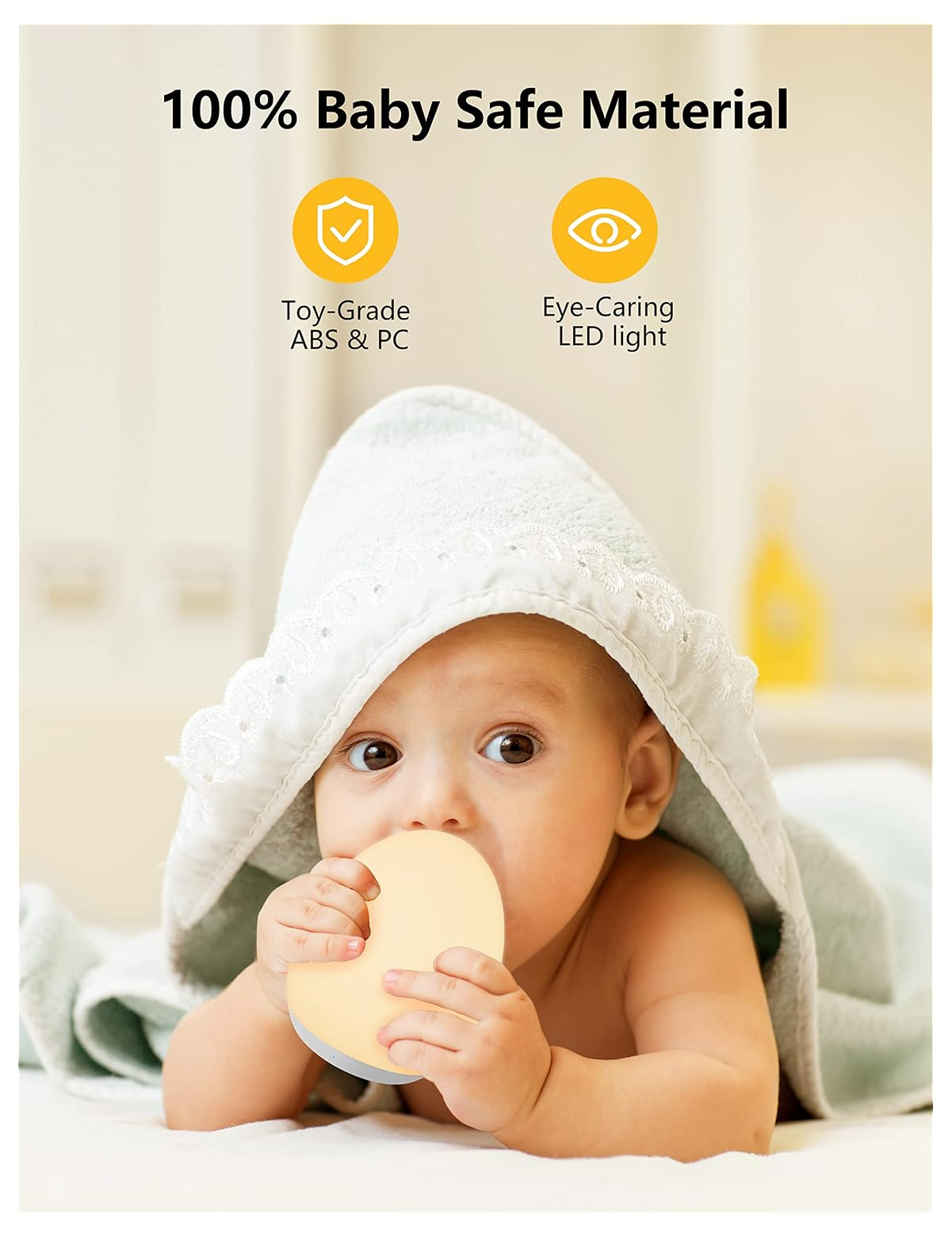 Ein Baby mit Handtuch auf dem Kopf hält eine runde, gelbe Lampe im Mund.