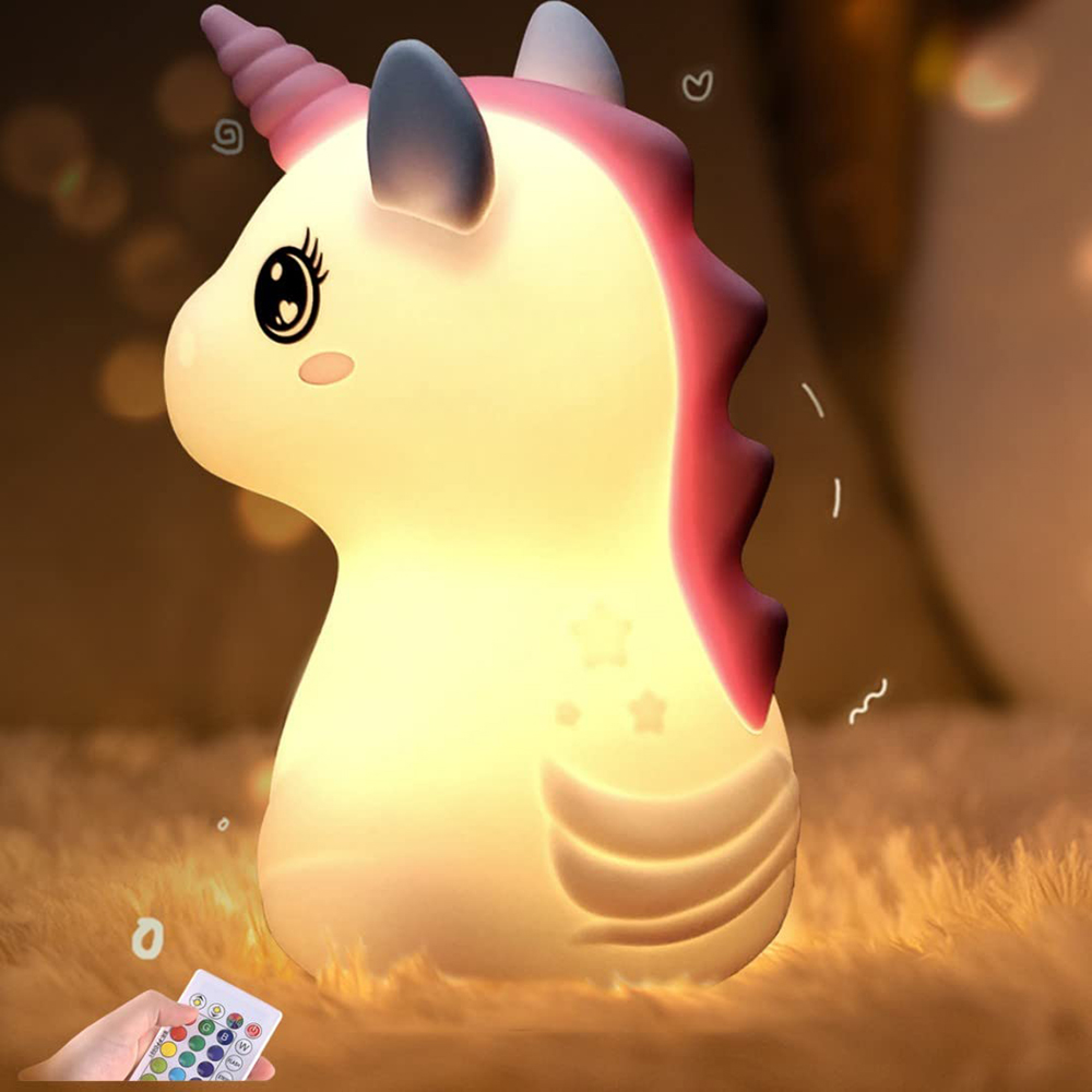 Ein beleuchtetes Einhorn-Nachtlicht auf flauschigem Fell, mit einer Hand und Fernbedienung im Vordergrund.