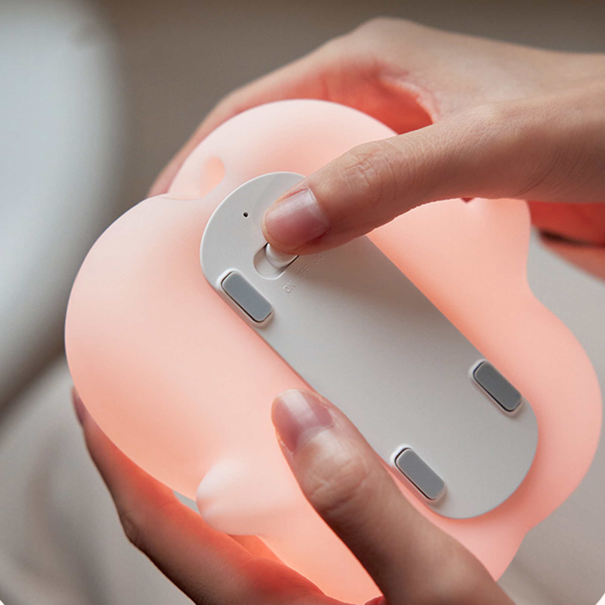 Person hält eine weiche, pinke Silikonlampe und schaltet sie ein.