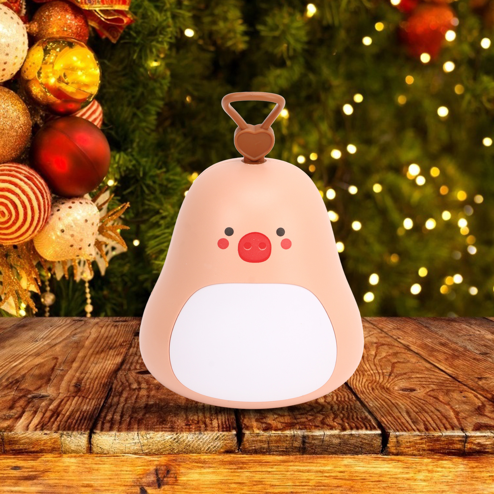 Ein rosafarbenes, tierähnliches Nachtlicht auf Holz, vor Weihnachtsbaum mit Lichtern.