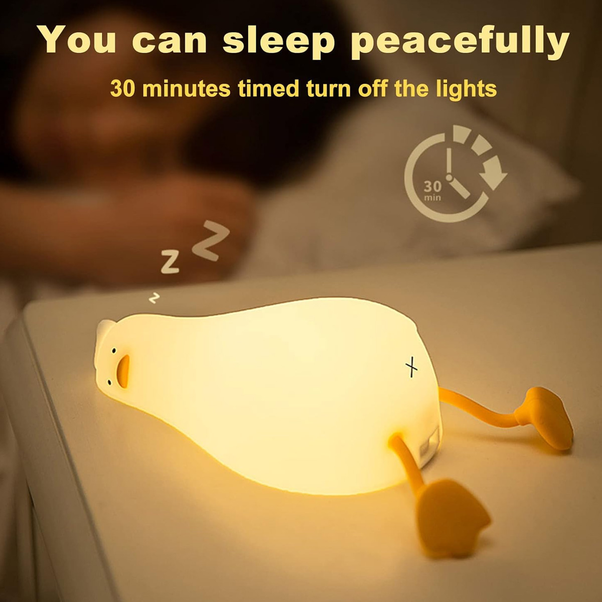 Eine leuchtende Enten-Nachtlampe liegt auf einem Tisch, während jemand im Hintergrund schläft.