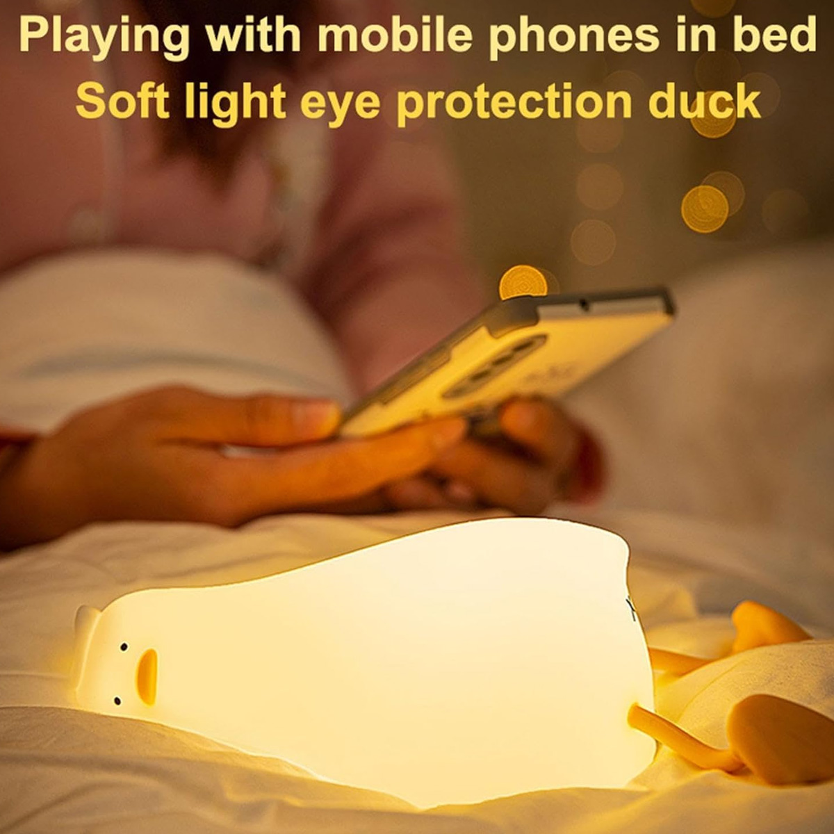 Ein leuchtendes Enten-Nachtlicht liegt auf einem Bett, während eine Person im Hintergrund ein Smartphone nutzt.