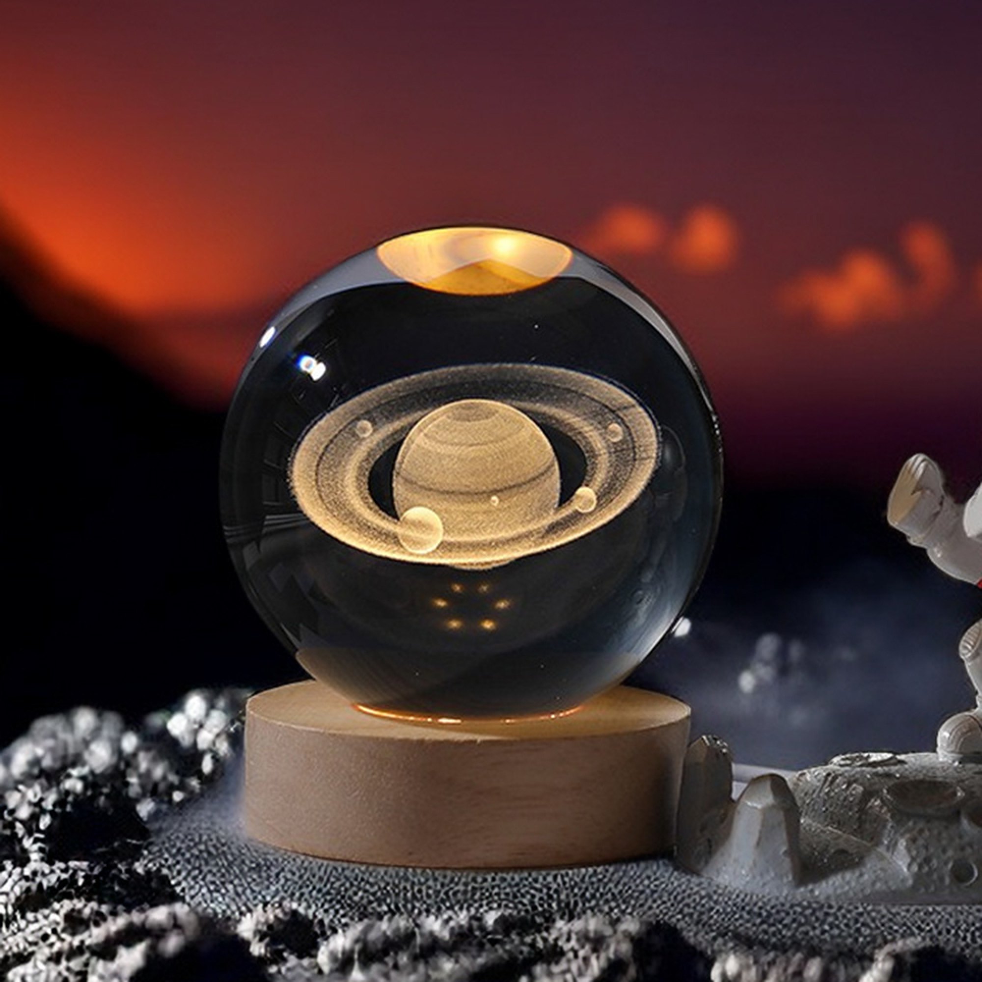 Eine leuchtende Kristallkugel mit eingraviertem Saturnmodell auf einem Holzsockel vor Weltraumhintergrund.