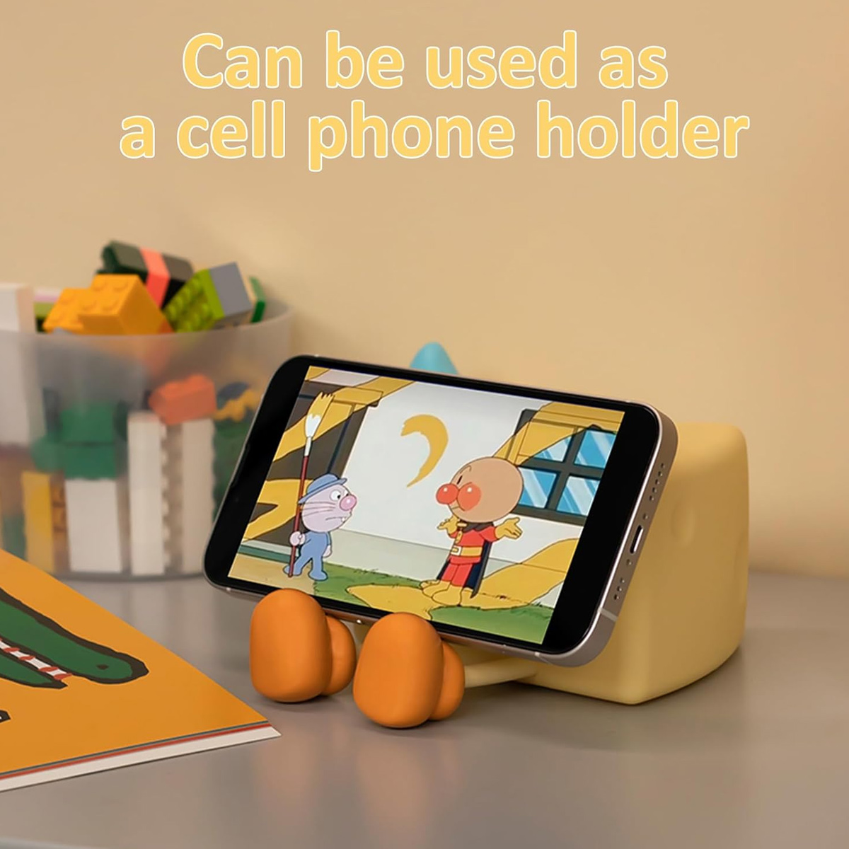 Ein Smartphone auf einem gelben Halter in Form einer Cartoon-Hand zeigt einen Anime.