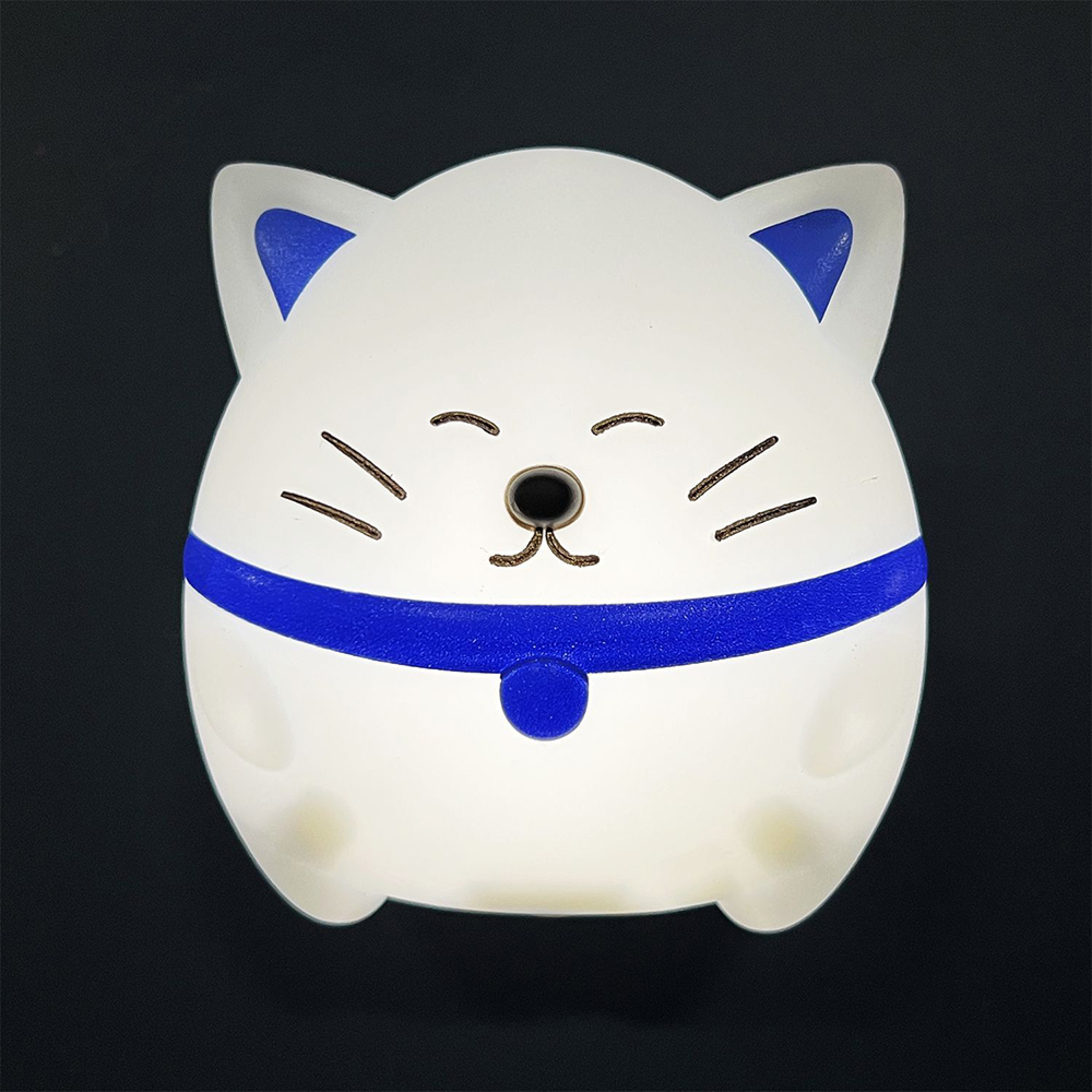 Eine weiße, katzenförmige Lampe mit blauen Ohren und Kragen auf schwarzem Hintergrund.