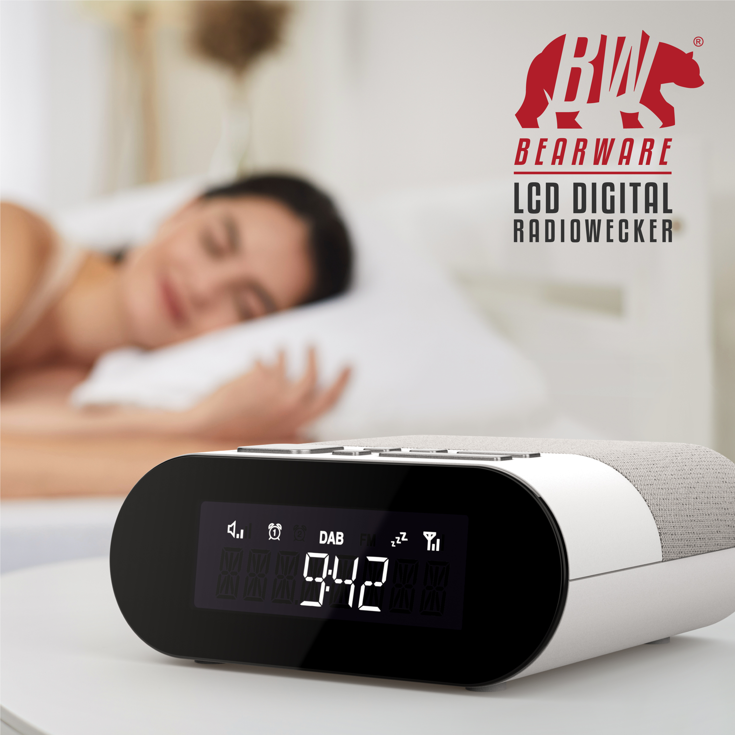 Ein weißer LCD-Radiowecker auf einem Nachttisch, im Hintergrund schläft eine Frau in einem Bett.