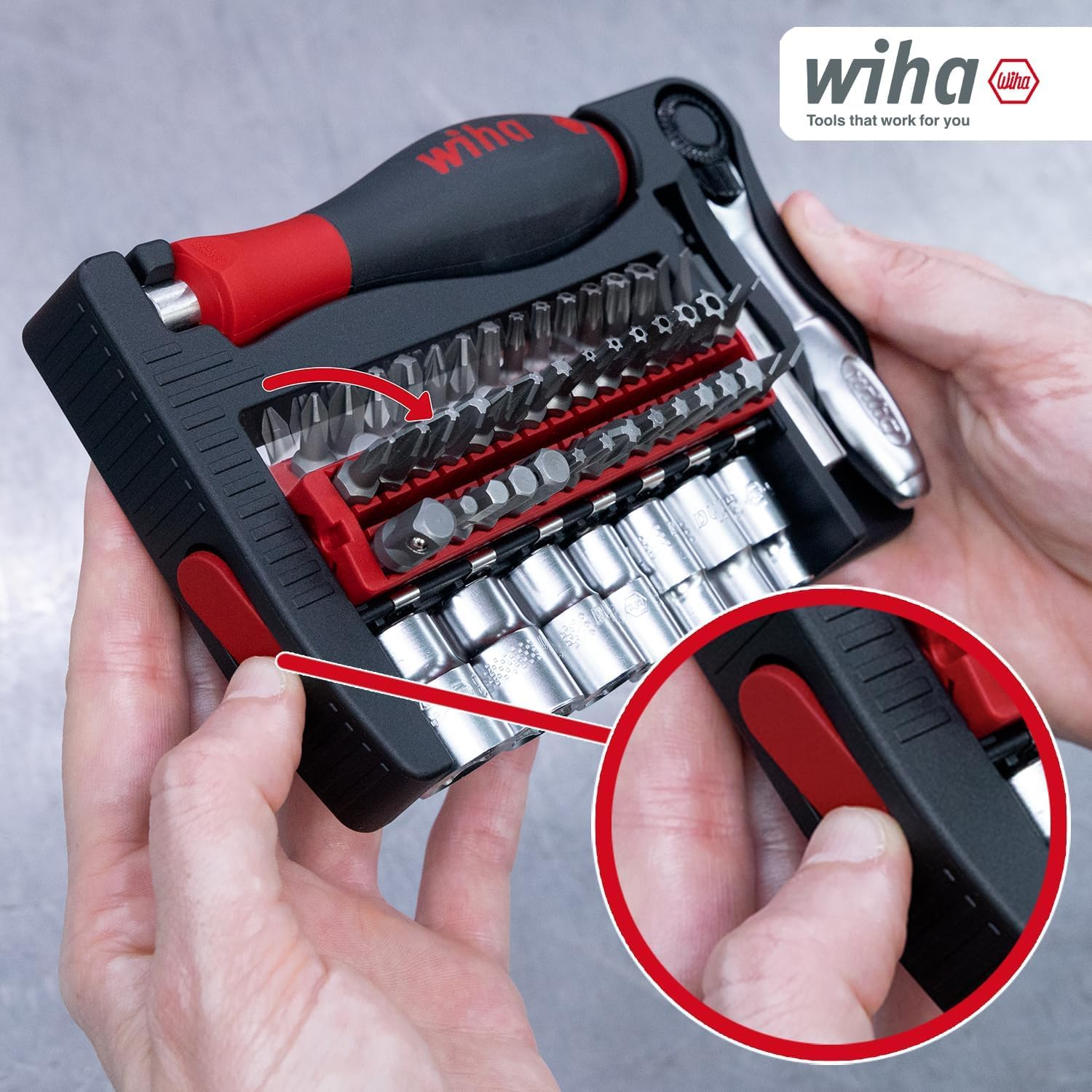 Persona tiene un set di attrezzi Wiha rosso e nero con inserti e bussole, con dettaglio ravvicinato del pulsante.