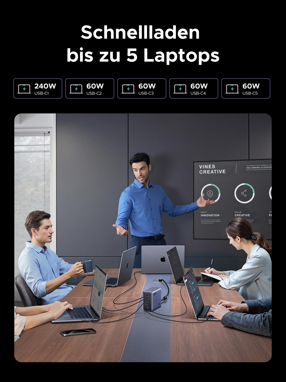 Un uomo fa una presentazione a colleghi con laptop. Un caricabatterie collega cinque laptop.