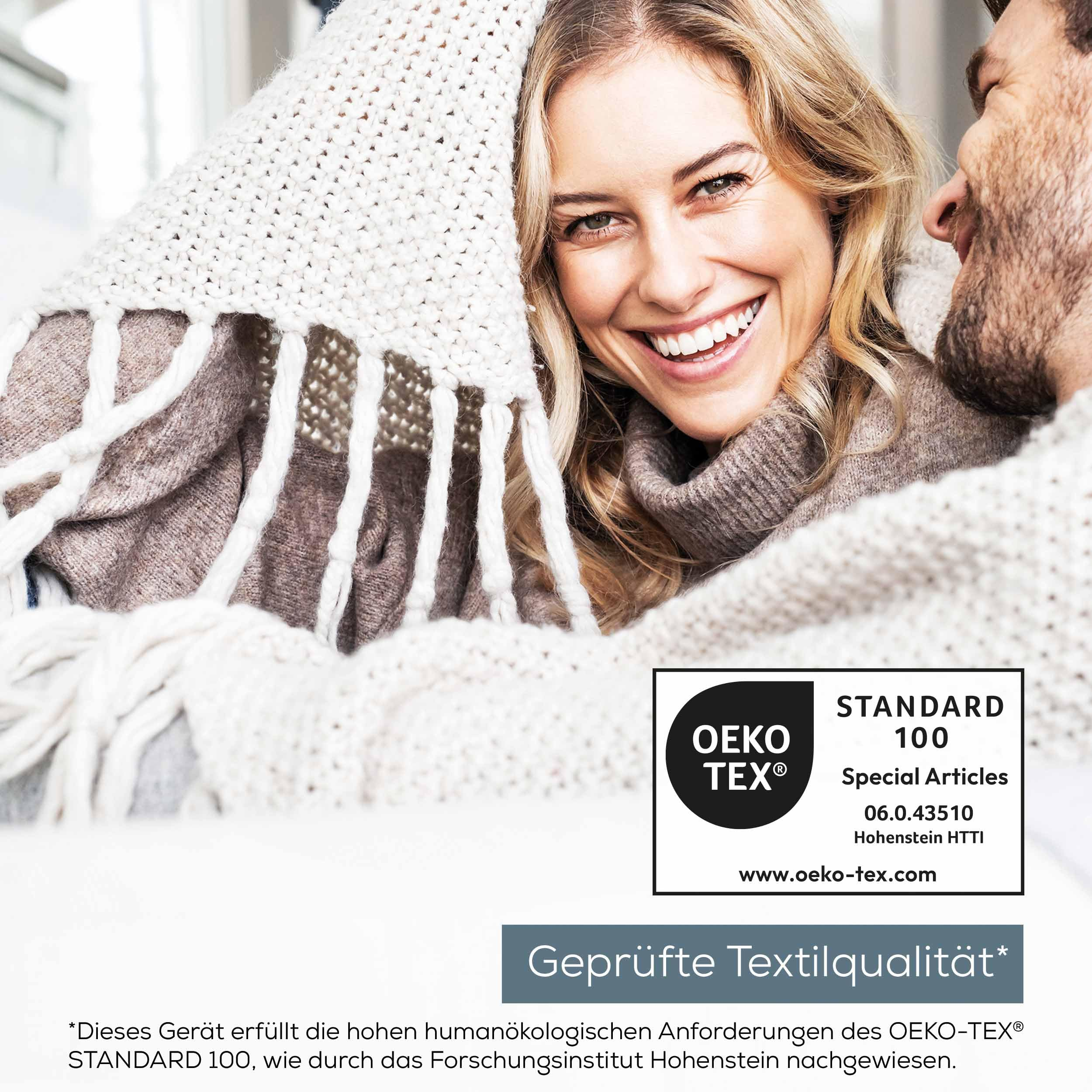 Felice coppia sotto una coperta bianca con marchio OEKO-TEX Standard 100.