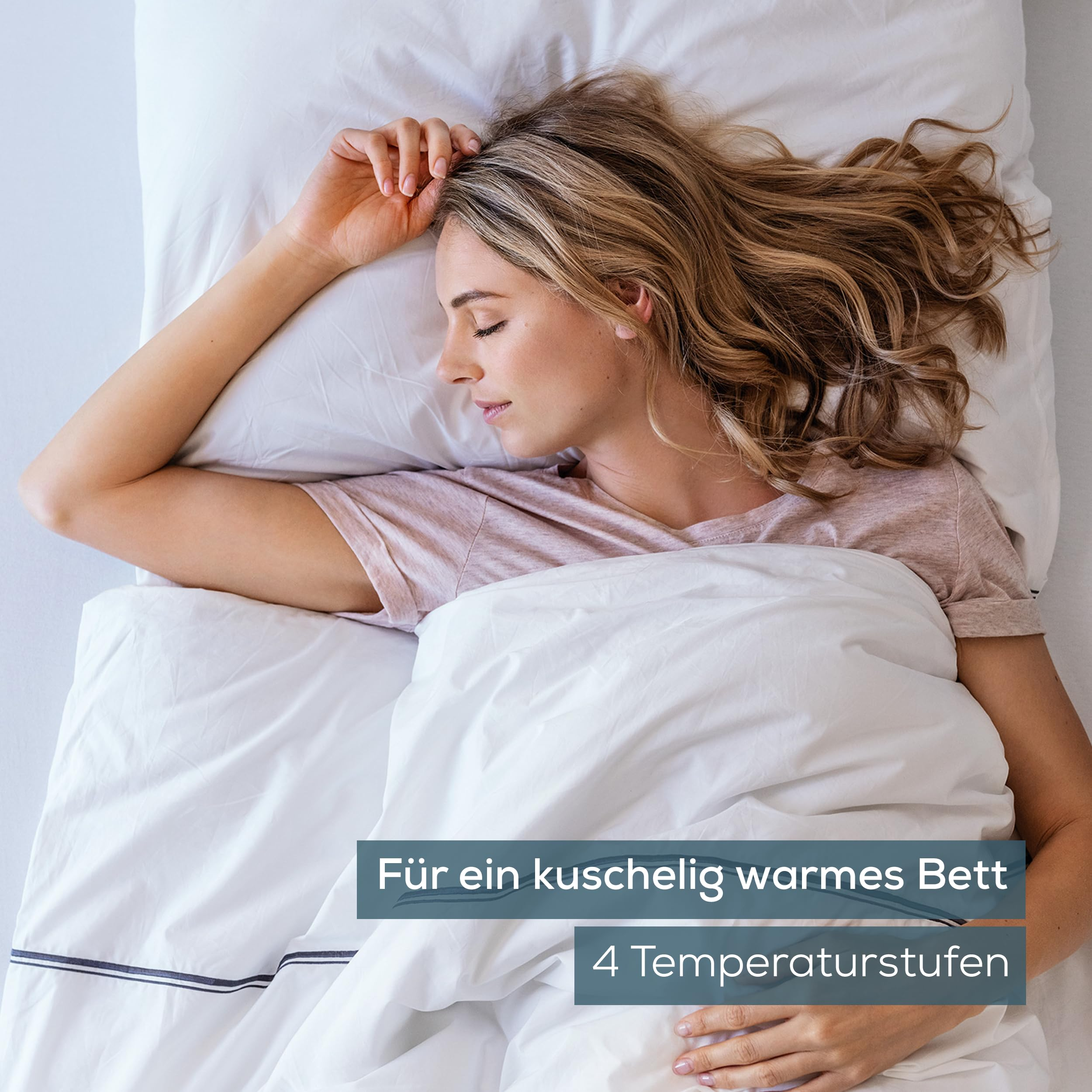 Donna che dorme serenamente in un letto bianco con piumino e cuscini.