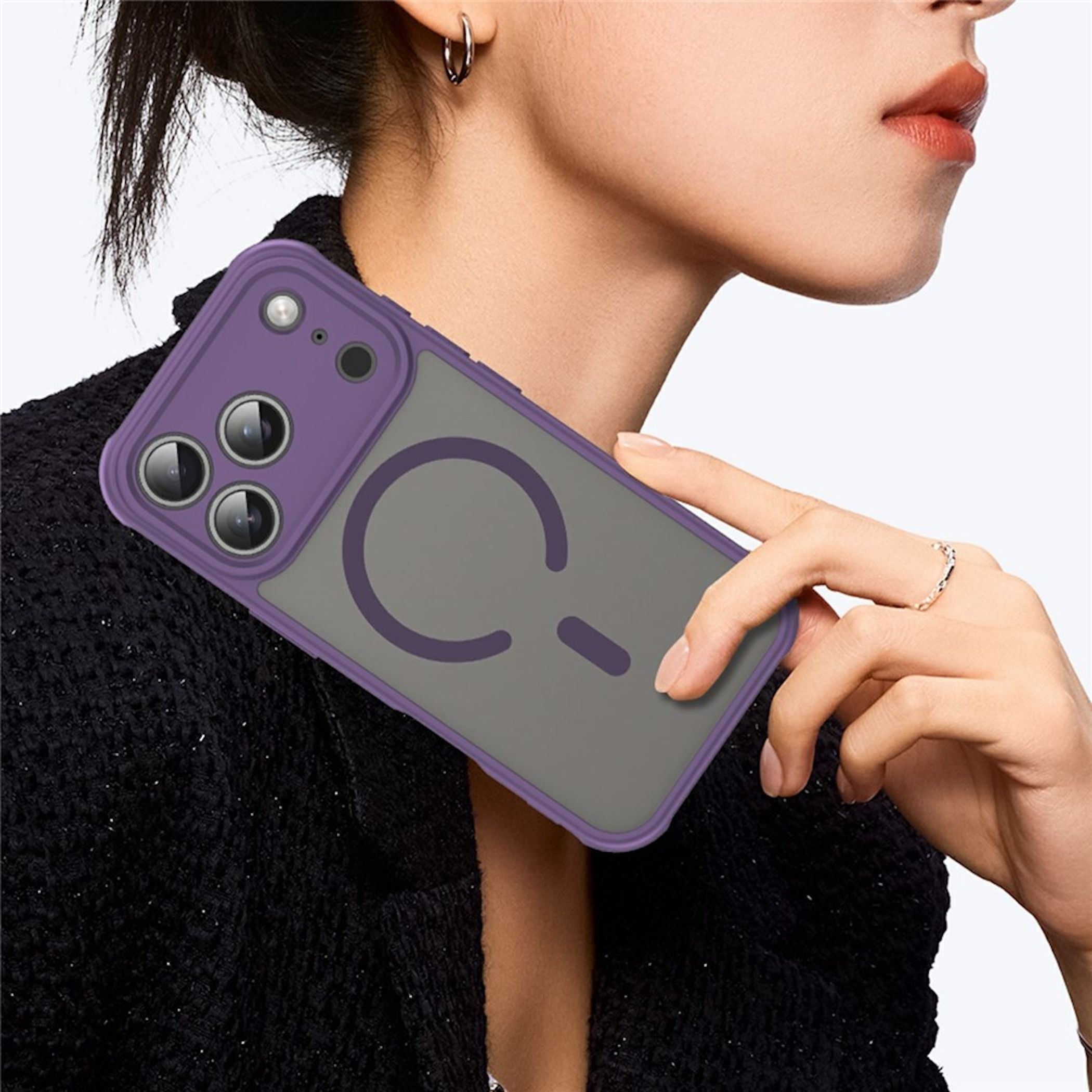 Una persona sostiene un smartphone con funda morada y logo de anillo magnético contra una parte superior negra.
