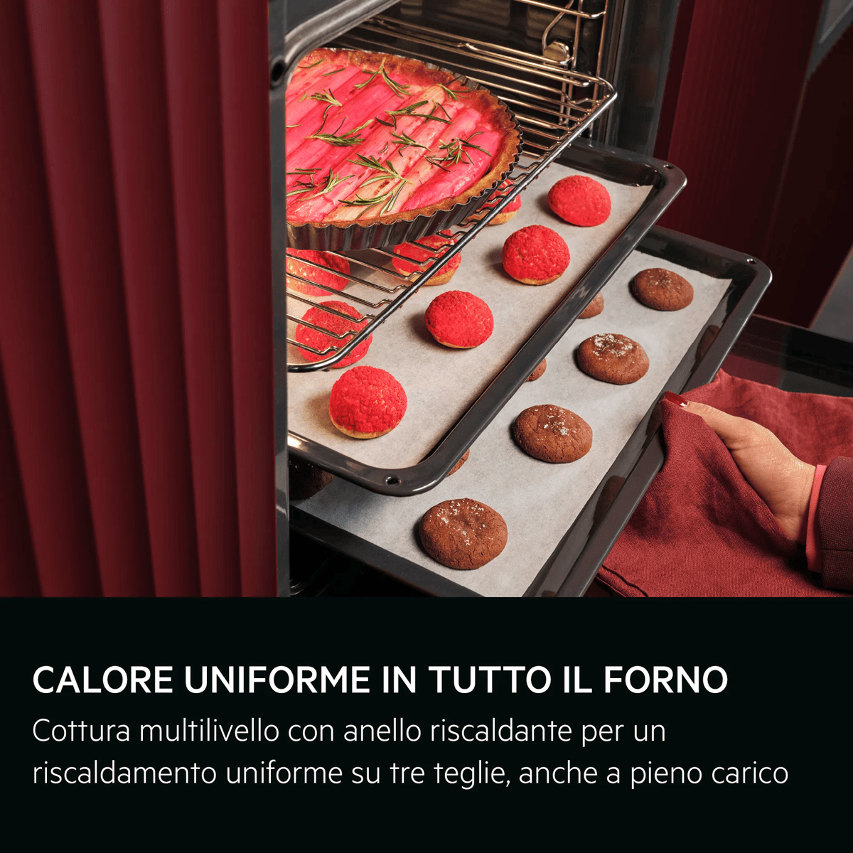 Forno con tre teglie contenenti una crostata, bignè rossi e biscotti.