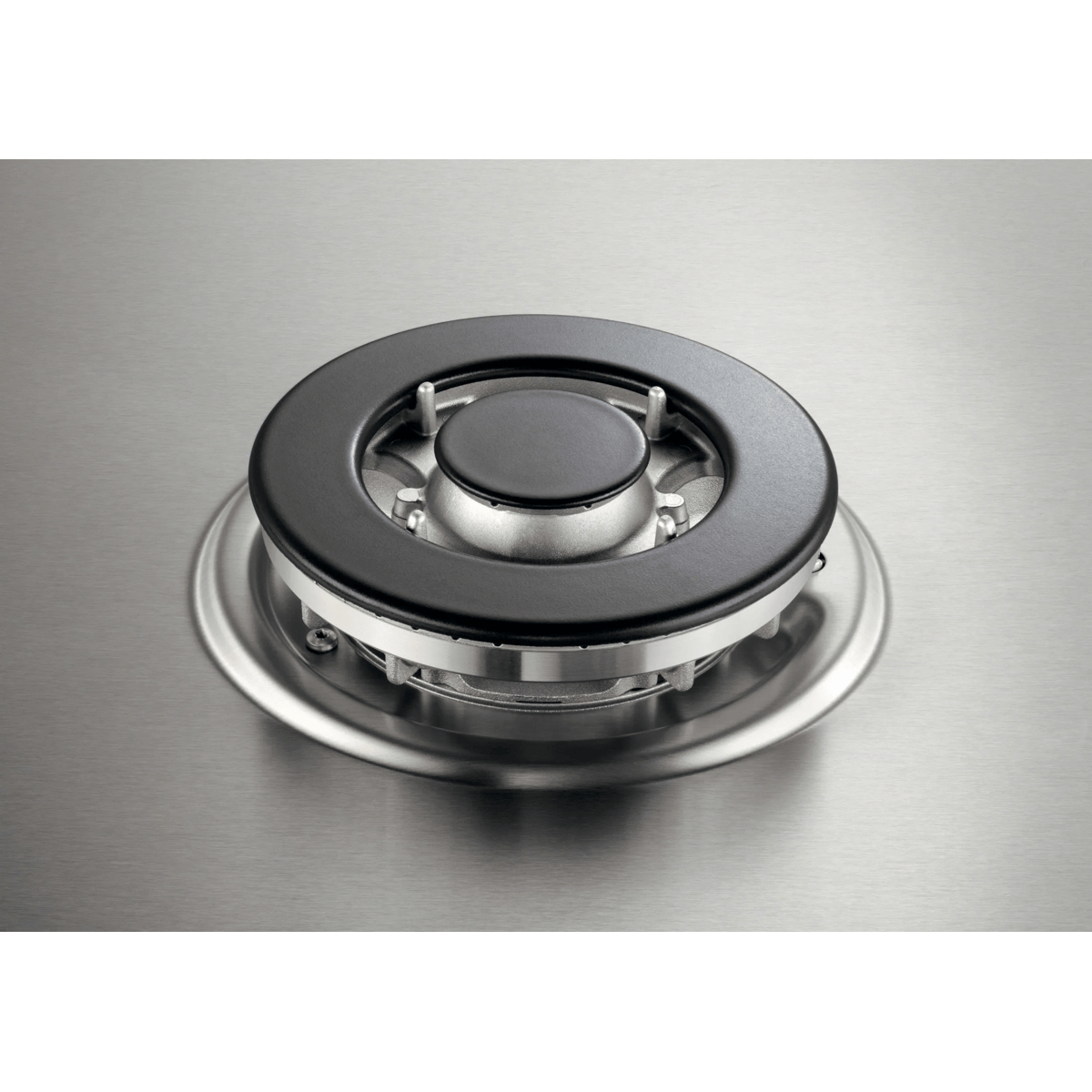 A round stainless steel gas burner with a black ring on a brushed stainless steel surface.