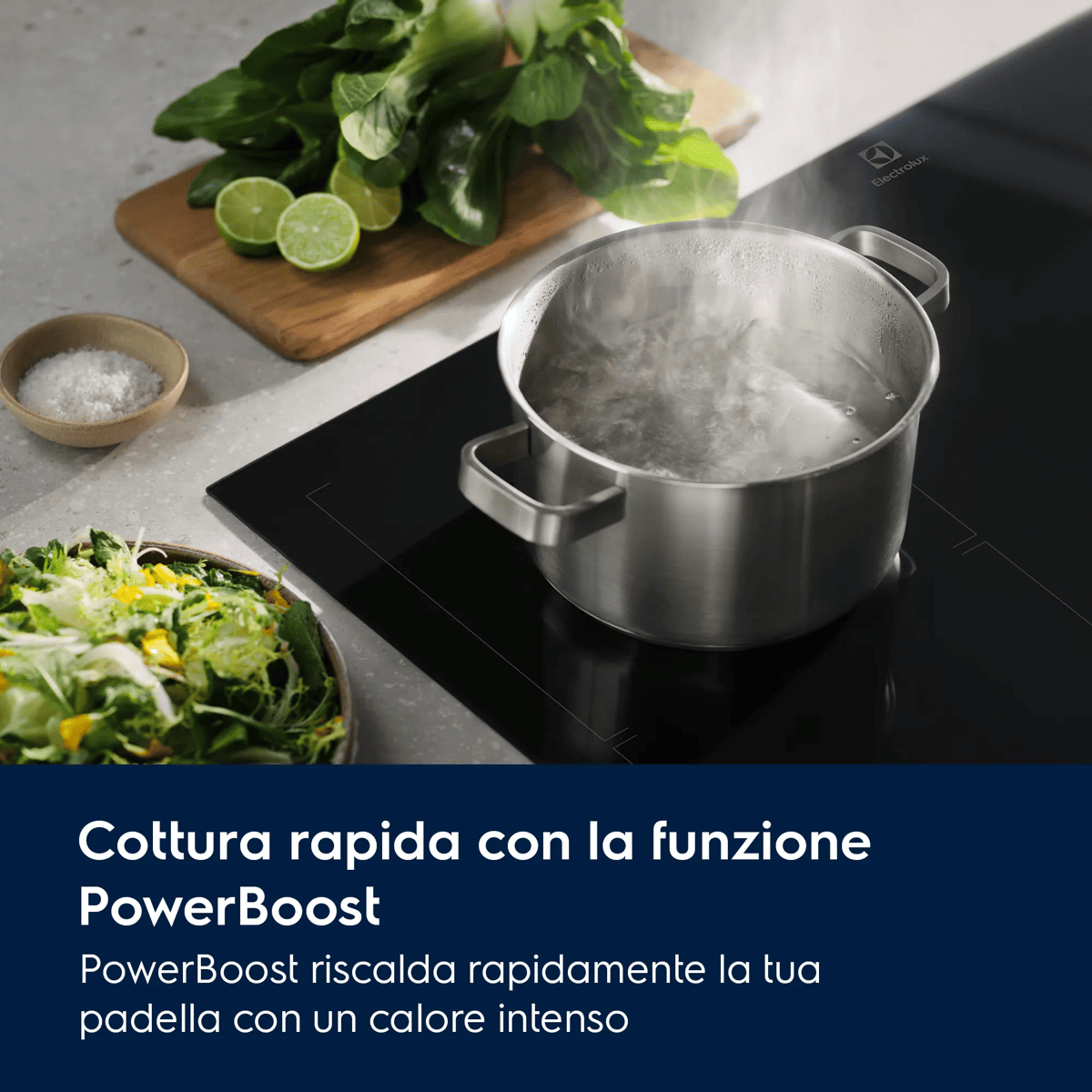 Una pentola che bolle su un piano a induzione, con insalata, lime e verdure su un tagliere.