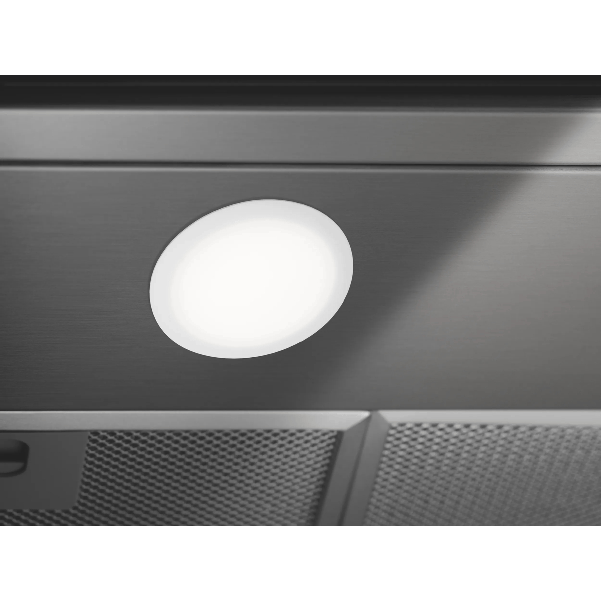 Primo piano di una luce LED circolare illuminata integrata nella superficie metallica di una cappa.