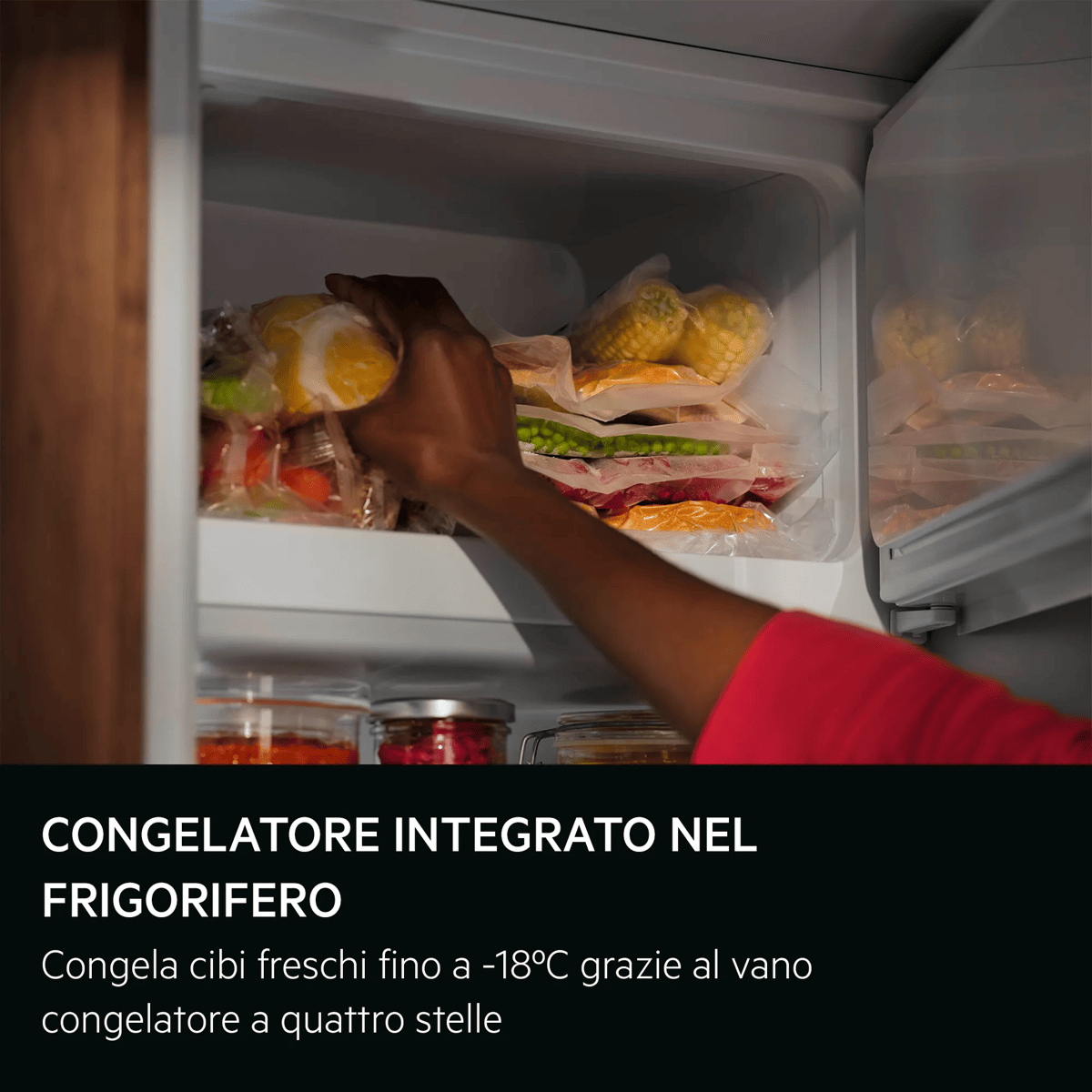 Una mano prende del cibo sottovuoto all'interno del vano congelatore di un frigorifero.