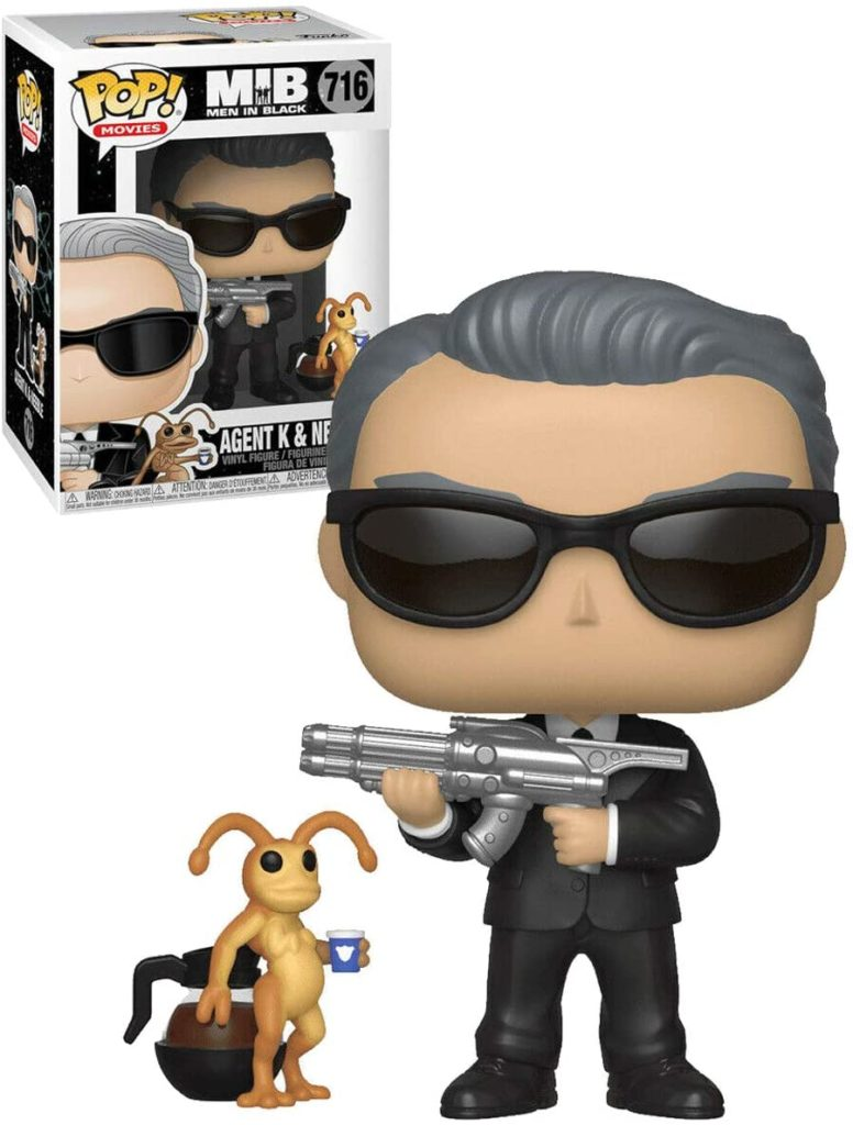 Funko Pop Figur von Agent K mit Waffe, neben einem kleinen Alien und seiner Box.