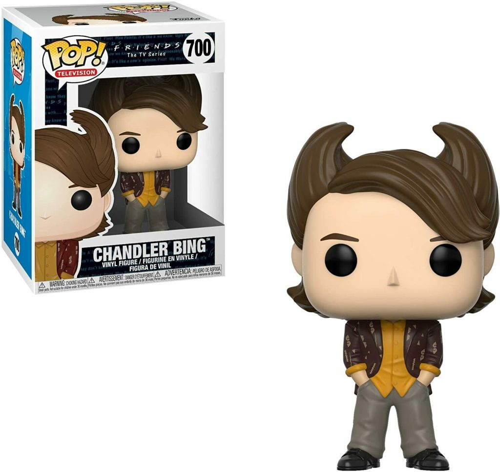 Eine Chandler Bing Funko Pop Figur mit großer brauner Frisur, gelbem Hemd und gemusterter Jacke neben ihrer Box.