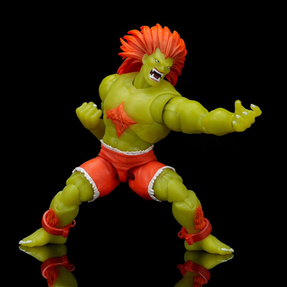 Grüne Actionfigur mit orangefarbenen Haaren und Shorts in Kampfpose auf schwarzem Grund.