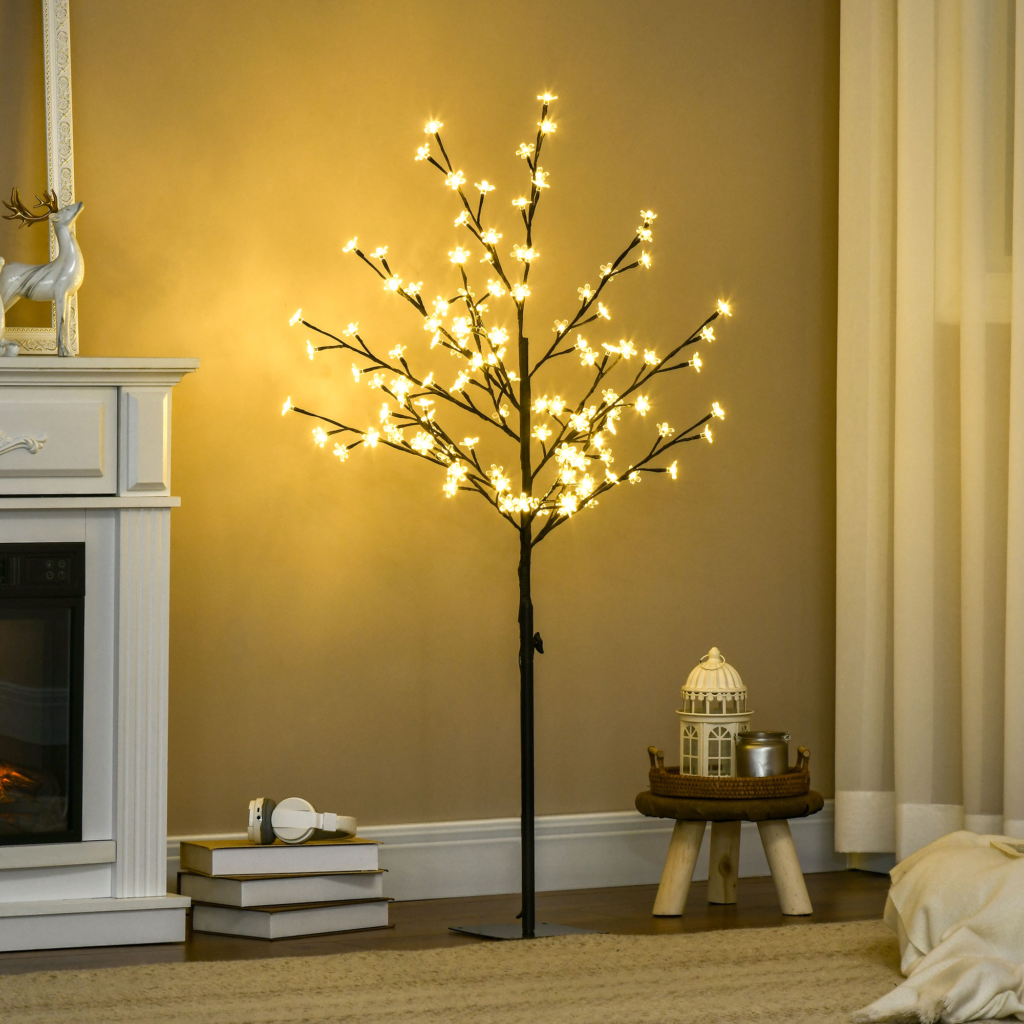 Árbol artificial iluminado con luces de flores blancas cálidas en una sala, flanqueado por una chimenea y un taburete.