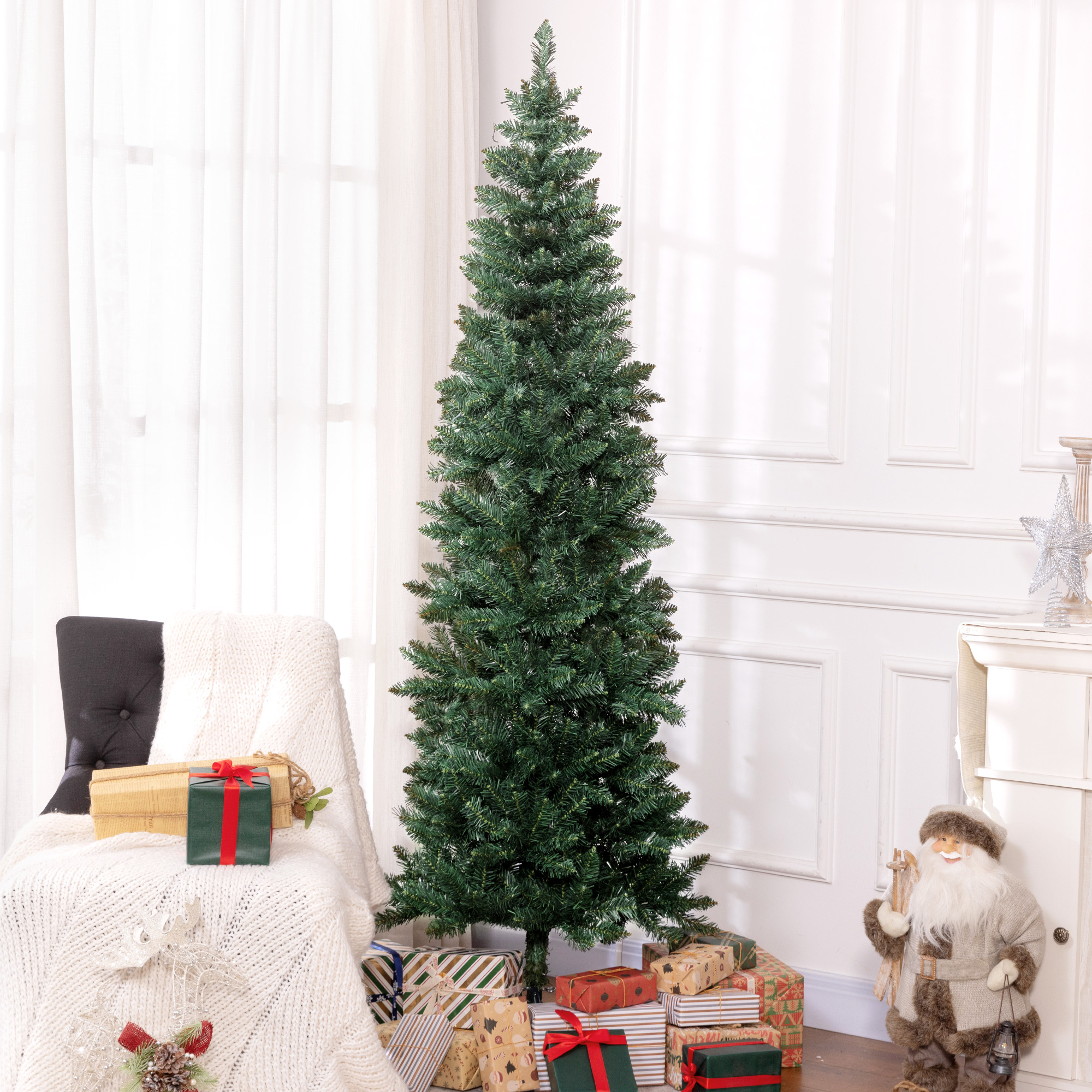 Un árbol de Navidad sin decorar se alza ante una pared blanca, rodeado de regalos, un sillón con manta y un Papá Noel.