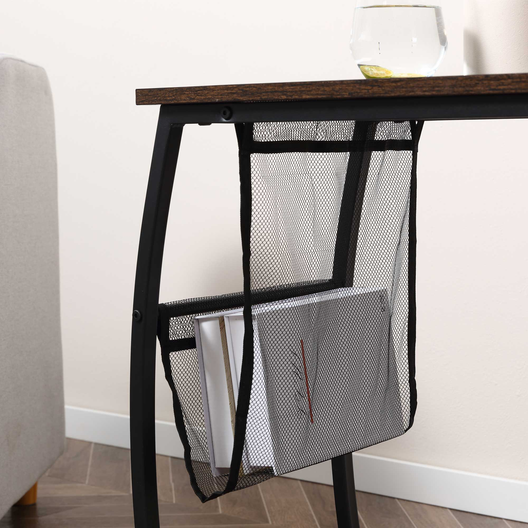 Una mesa auxiliar de madera y metal tiene un bolsillo de malla negra en el lateral con revistas.