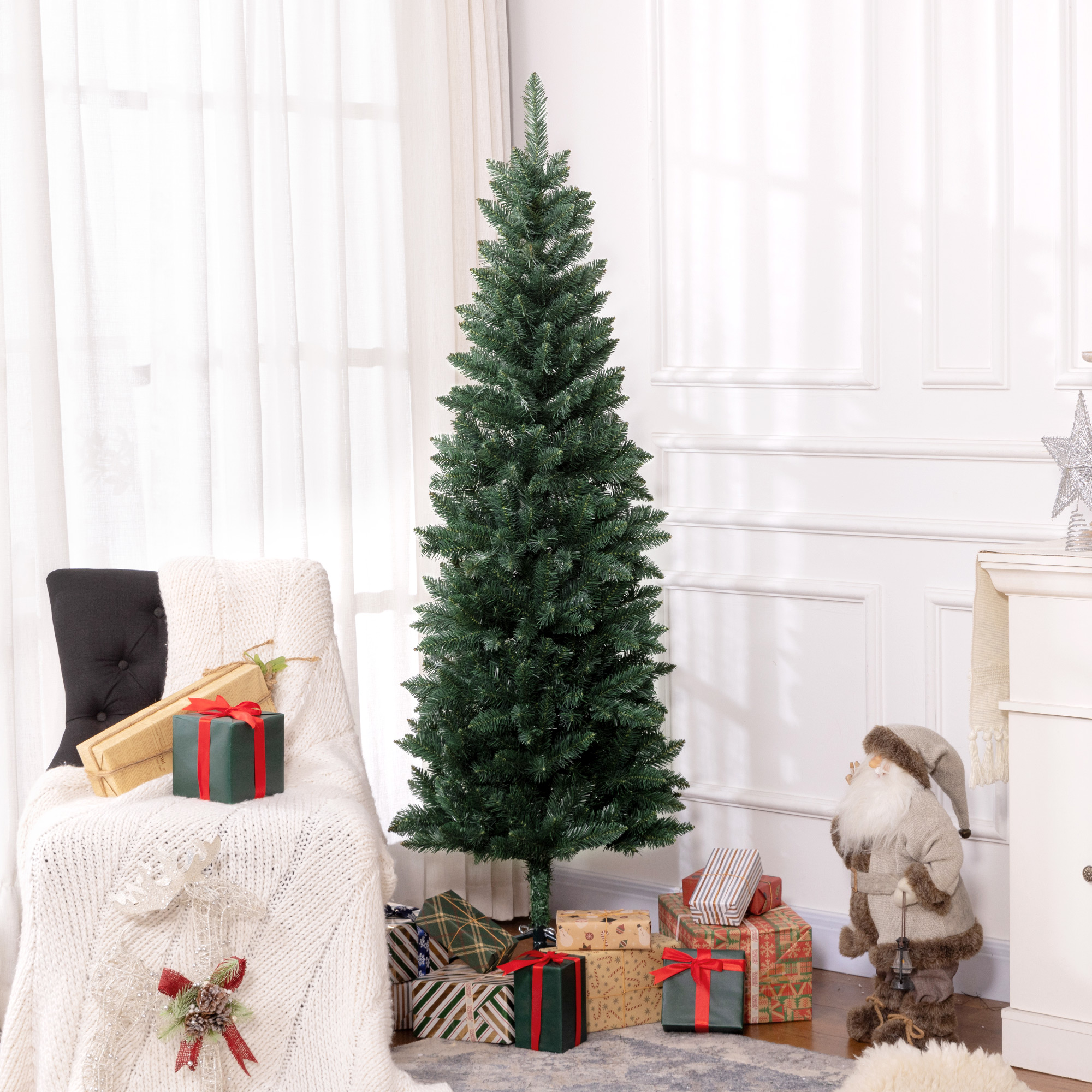 Una habitación decorada con árbol de navidad verde, regalos, figura de Papá Noel y una silla con manta blanca.