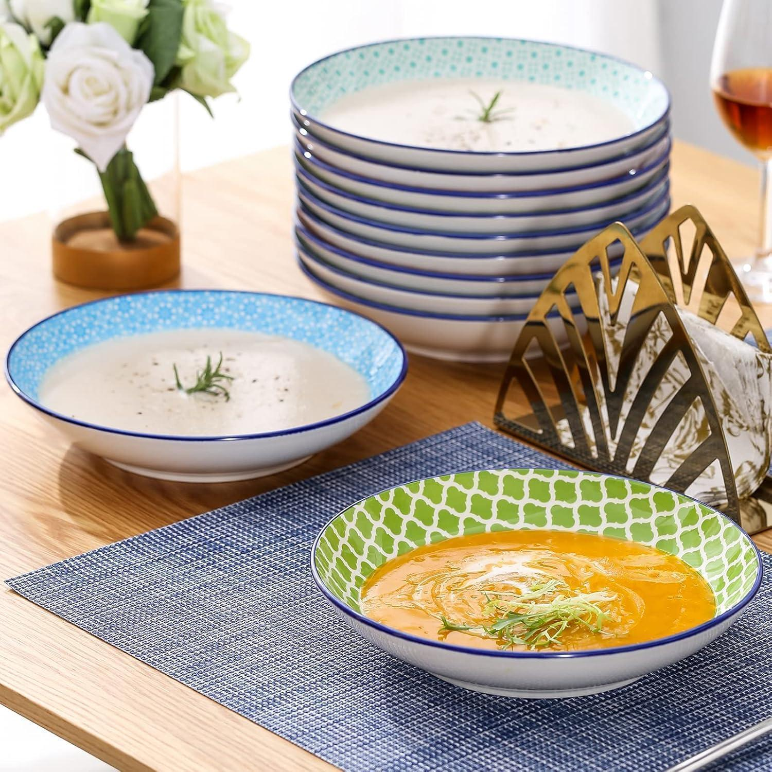 Ciotole di zuppa colorate con zuppa su un tavolo di legno, con portatovaglioli e fiori.