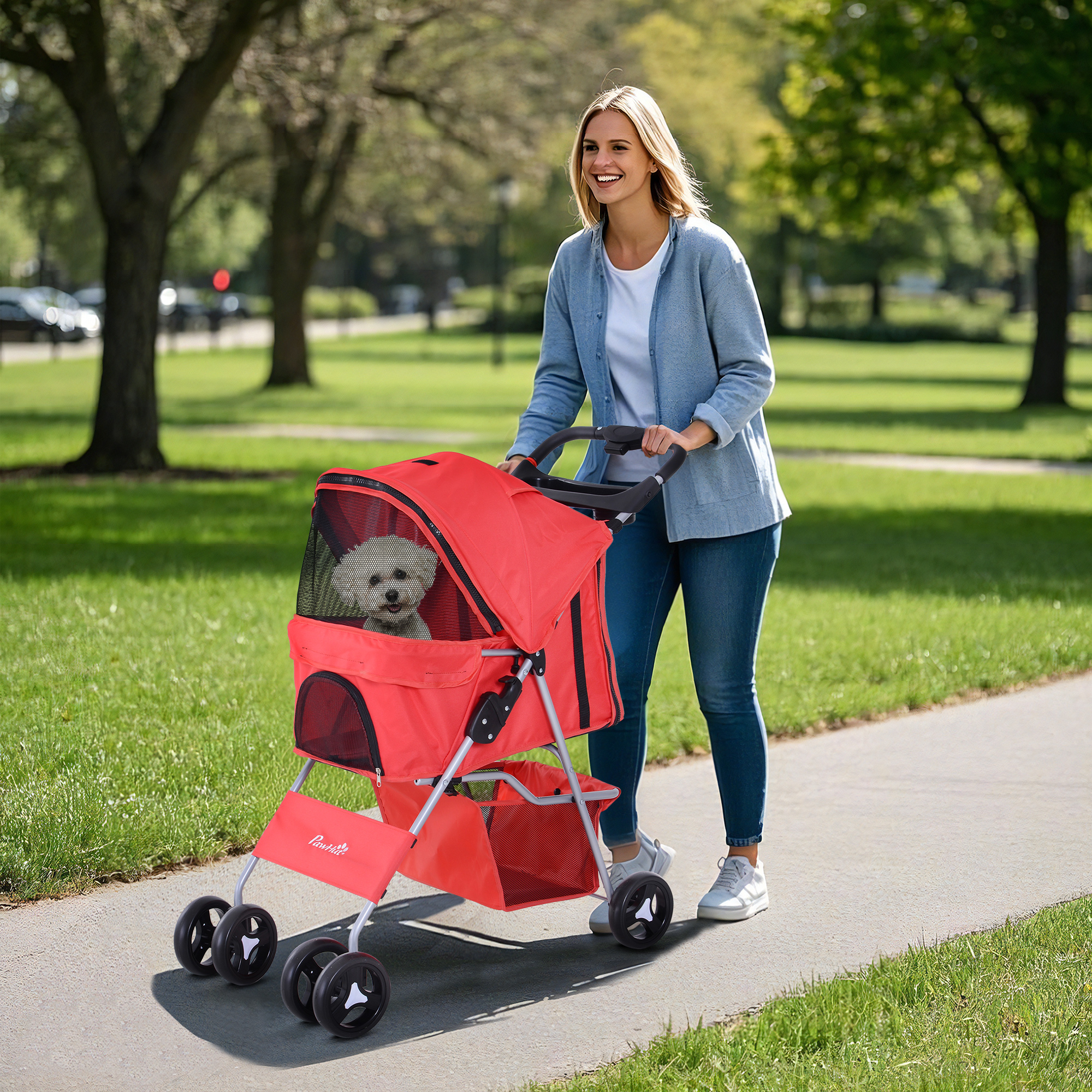 Una donna bionda sorridente spinge un passeggino rosso per animali con un piccolo cane bianco.