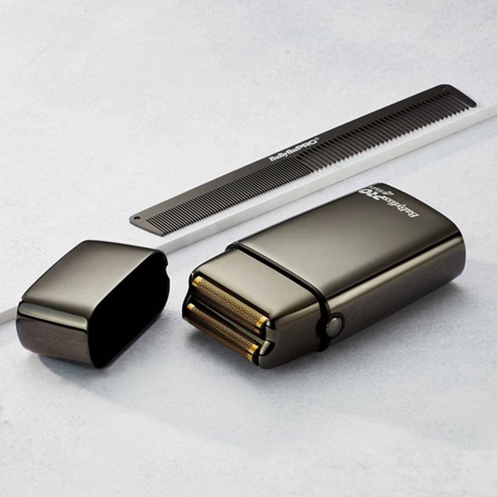 Ein metallic-grauer elektrischer Rasierer mit offenem Deckel und einem schwarzen Kamm auf weißem Hintergrund.