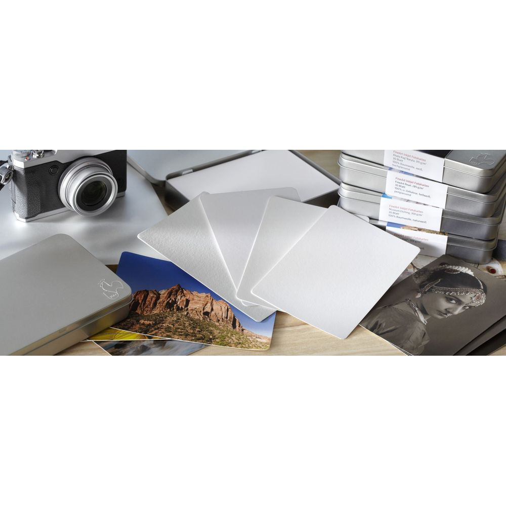 Leere Fotokarten, eine Kamera und Metallboxen auf einem Holztisch.