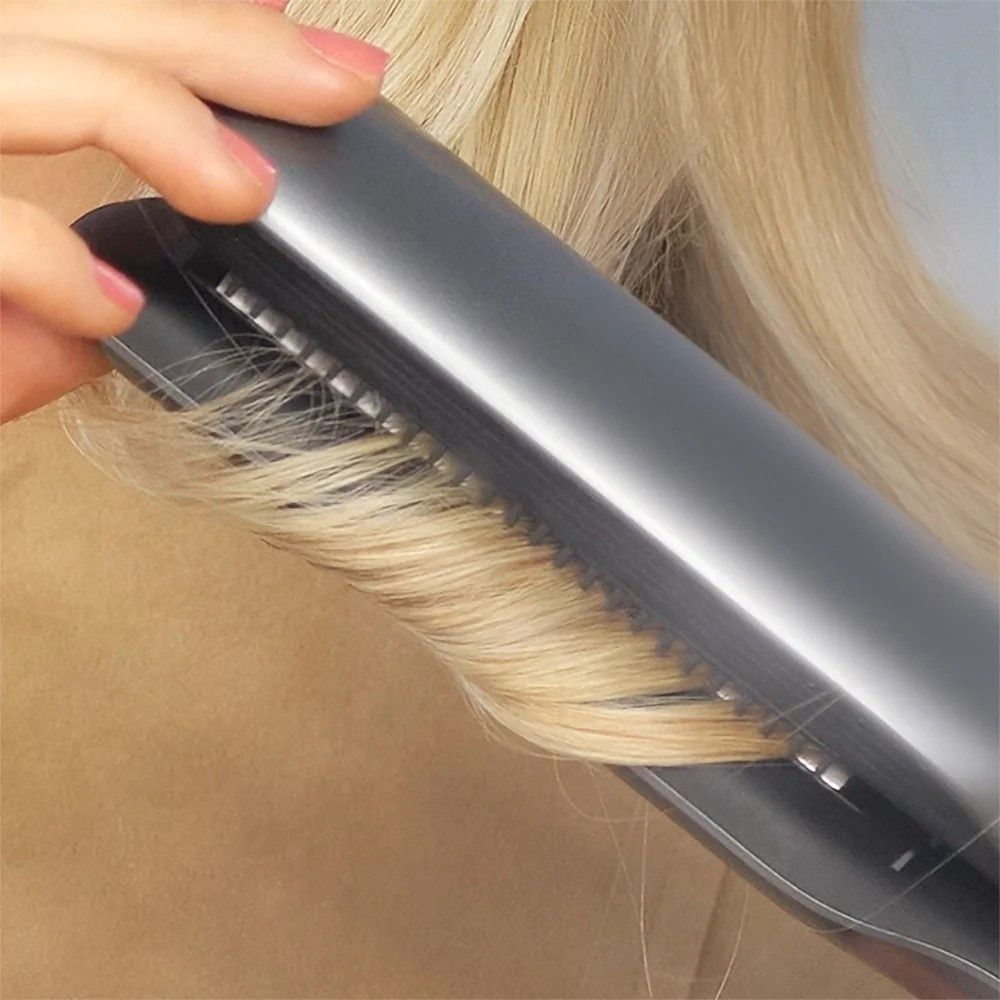 Glätteisen mit Kammzähnen gleitet durch langes, blondes Haar.