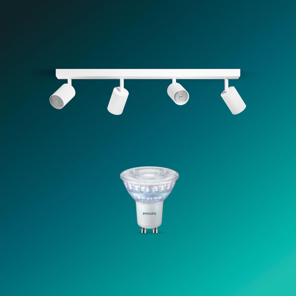 Eine weiße Deckenleiste mit vier verstellbaren Strahlern und eine Philips LED-Lampe vor tealblauem Hintergrund.