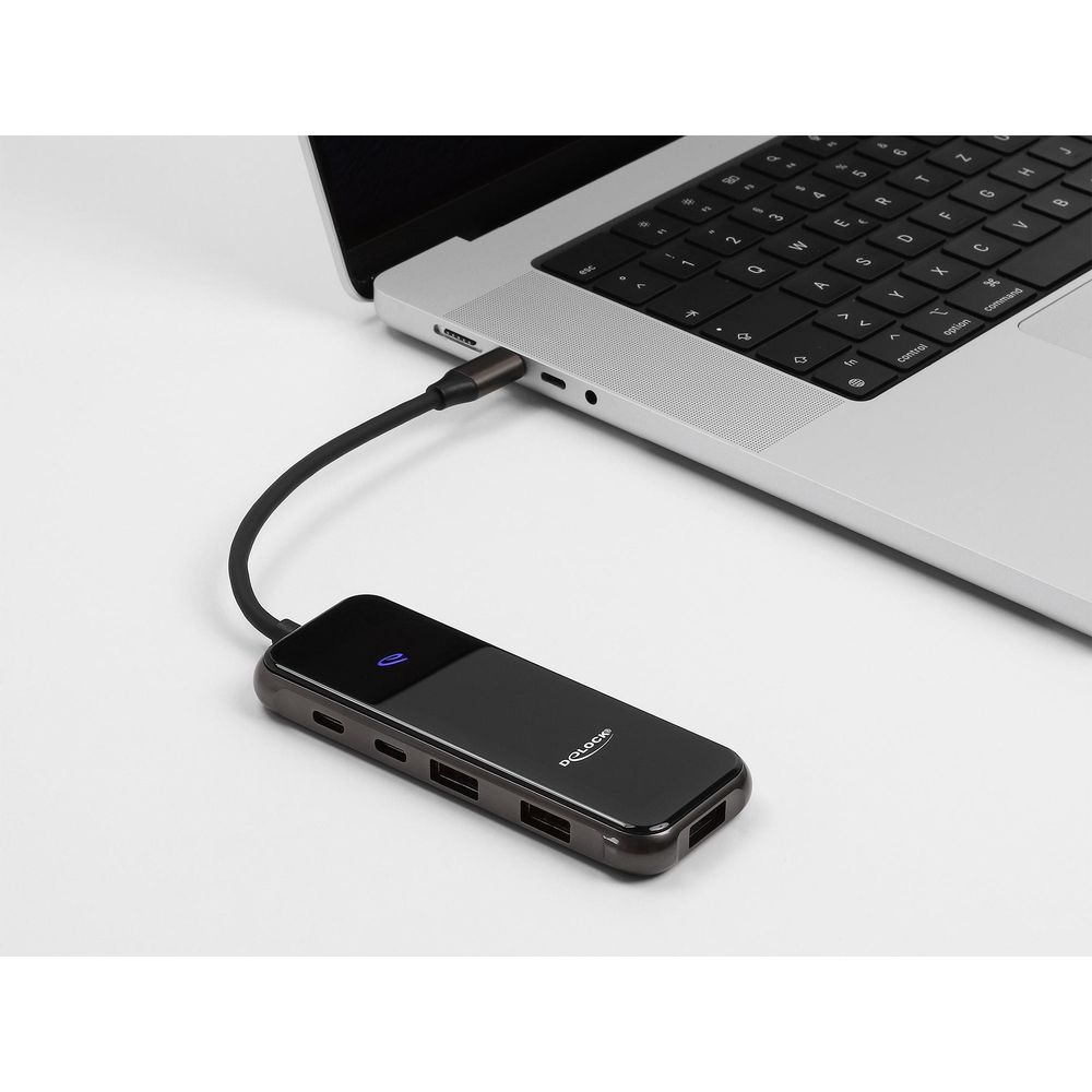 Un hub USB-C nero è collegato tramite cavo al lato di un computer portatile argentato.