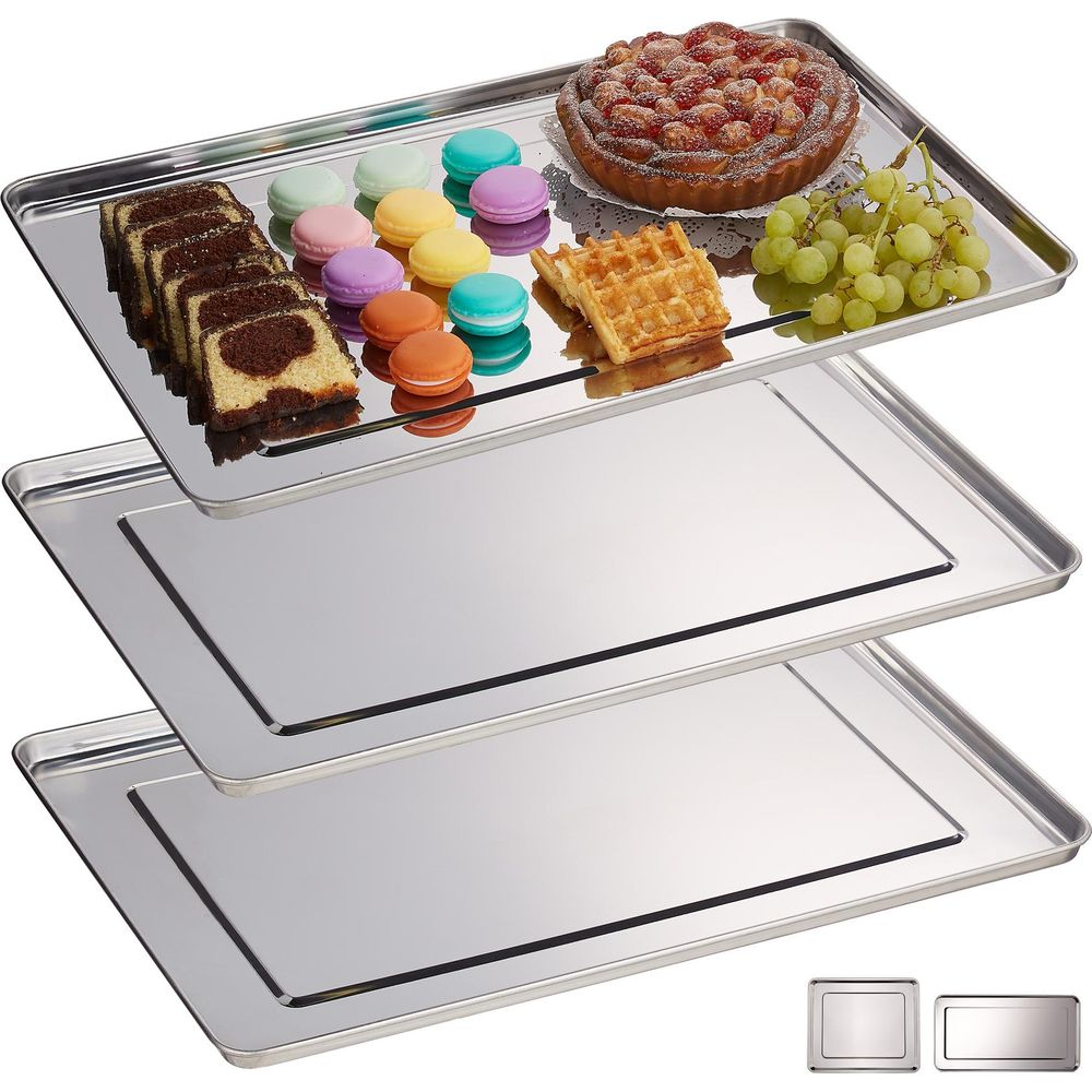 Drei gestapelte Edelstahlbleche, das obere mit Kuchen, Makronen, Beerenkuchen, Waffeln und Trauben.