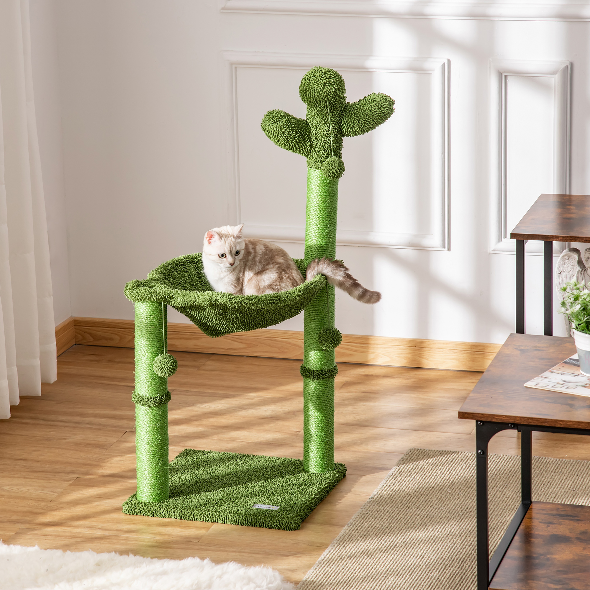 Un gatto crema e tigrato riposa su un tiragraffi verde a forma di cactus.