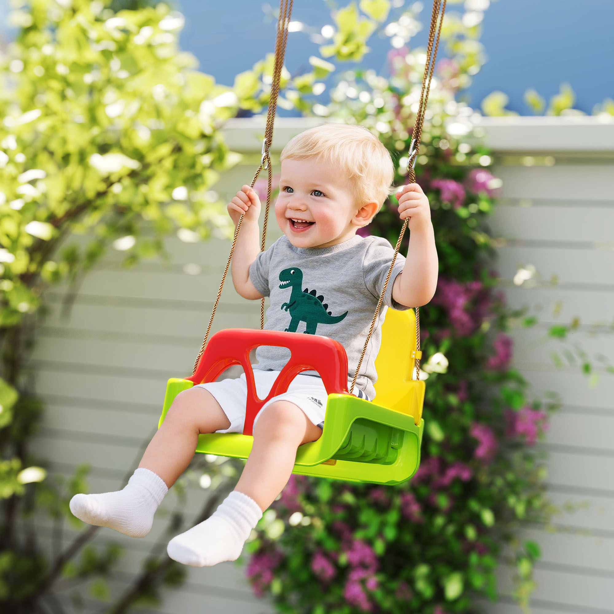 Un bambino piccolo sorride felice su un'altalena colorata in un giardino fiorito.