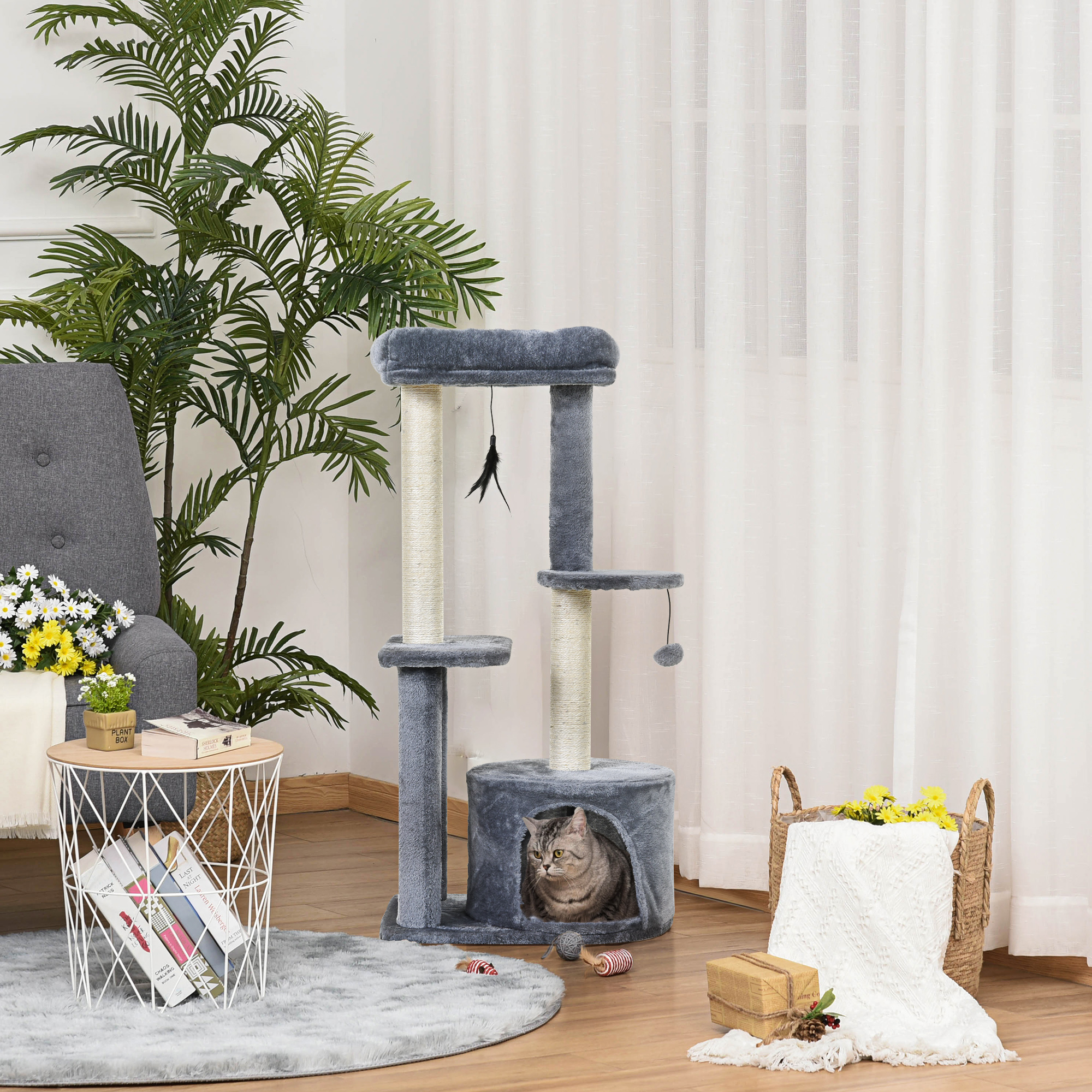 Albero per gatti grigio in stanza con poltrona, pianta e cesta.