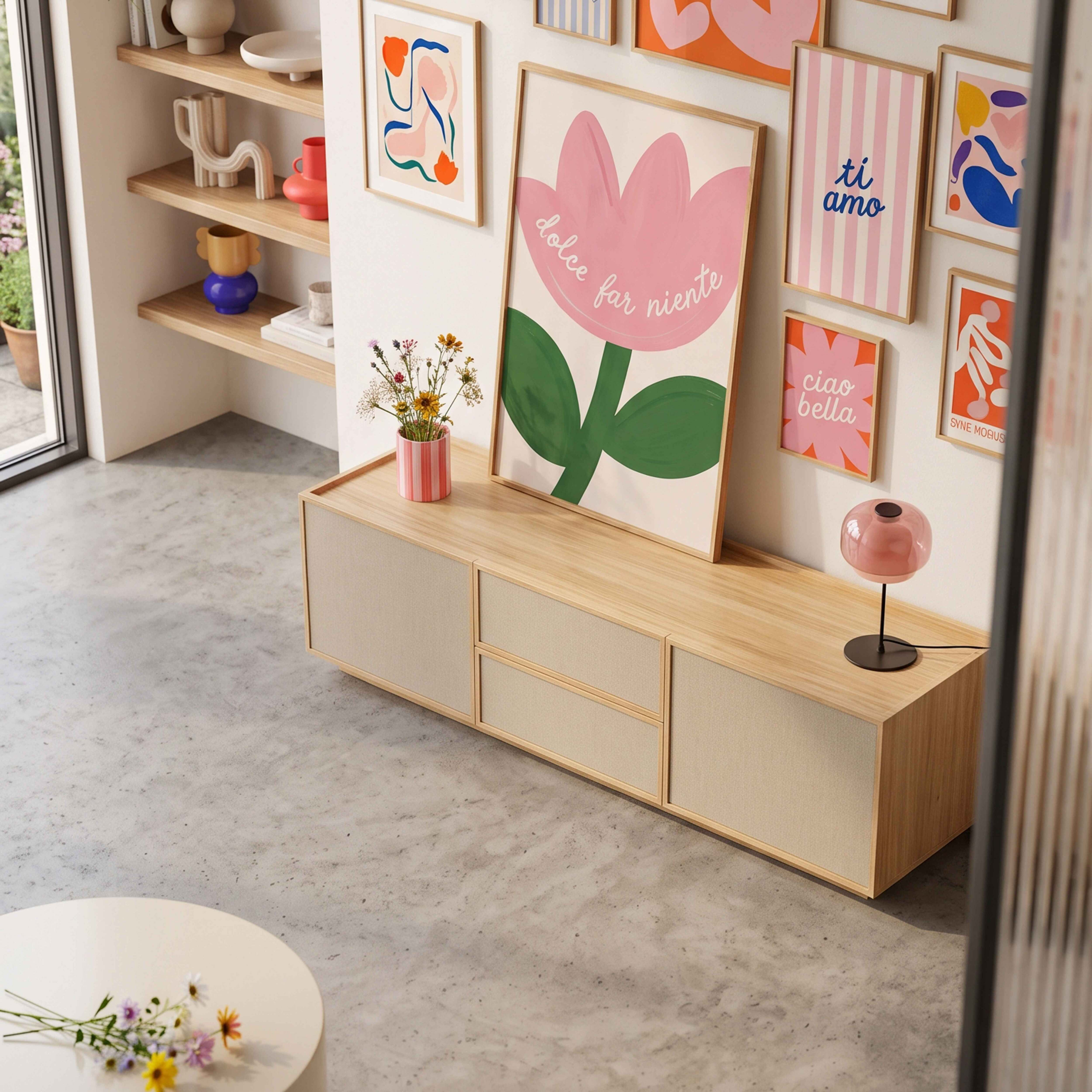 Wohnzimmer mit Holzschrank, rosa Blumengrafik und farbenfrohen Postern an der Wand.