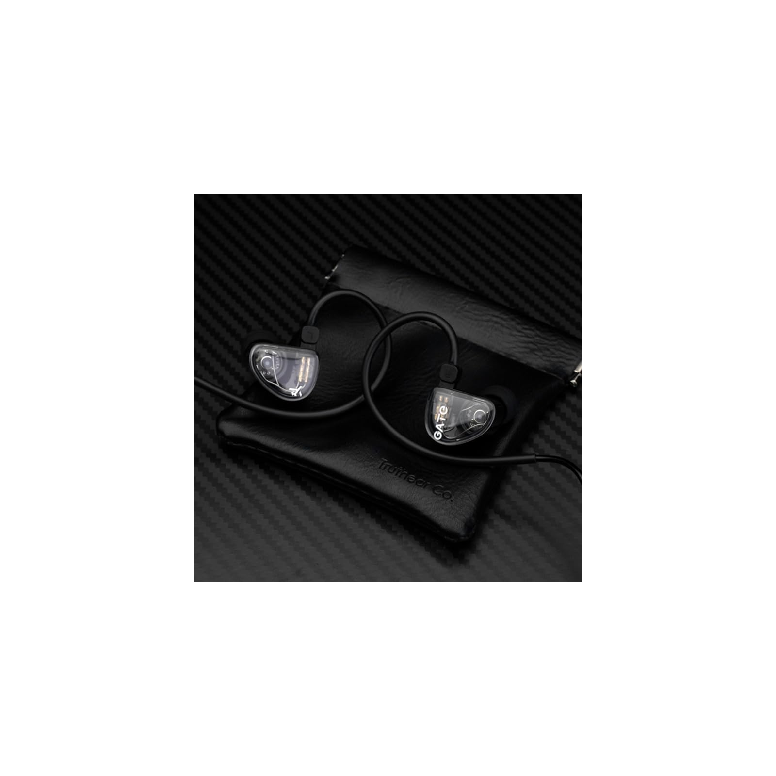 Transparente In-Ear-Kopfhörer mit schwarzem Kabel liegen auf einer kleinen schwarzen Ledertasche.