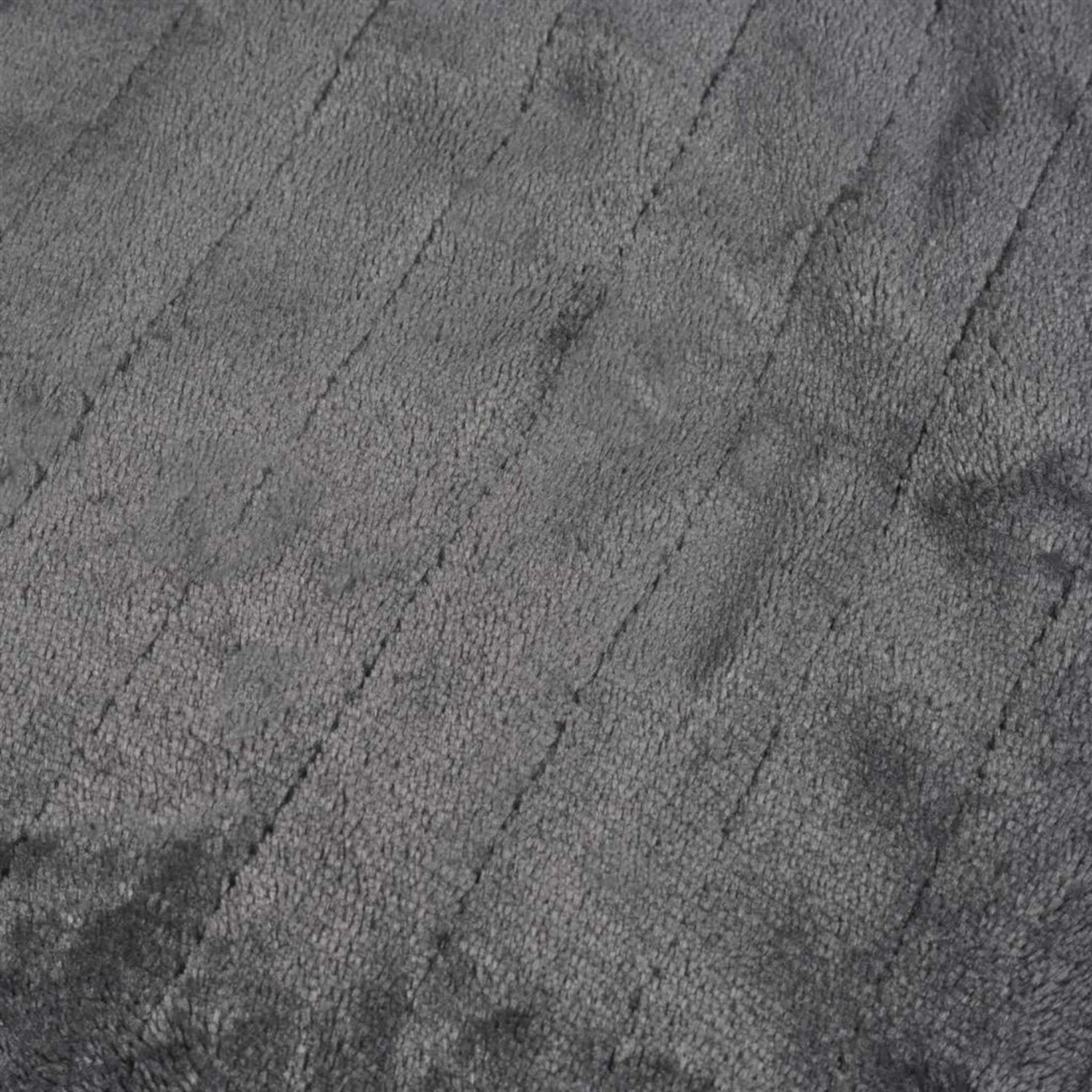 Ein geschlossener Blick auf eine weiche, graue Plüschdecke mit feinen Rillen.
