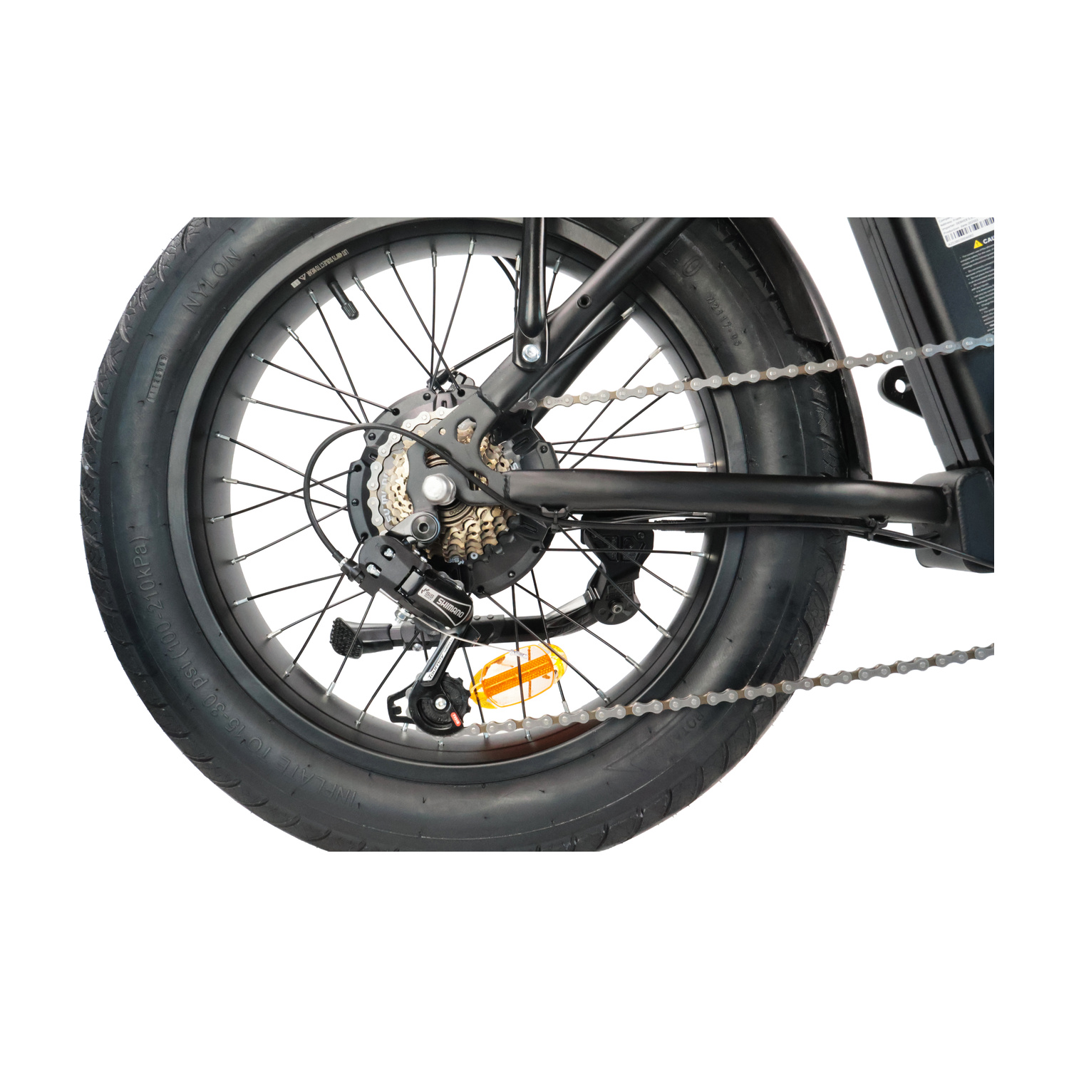 Primo piano della ruota posteriore di una bicicletta con pneumatico largo, marce, catena e un piccolo catadiottro arancione.