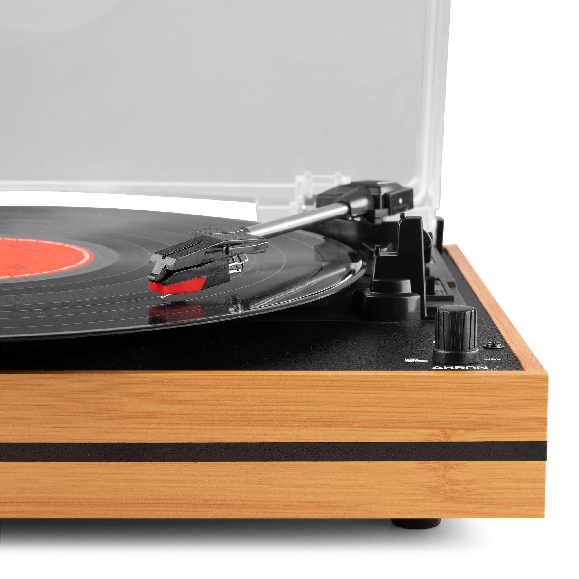 Un tocadiscos de madera con cuerpo negro, aguja roja y negra y cubierta transparente sobre fondo blanco.