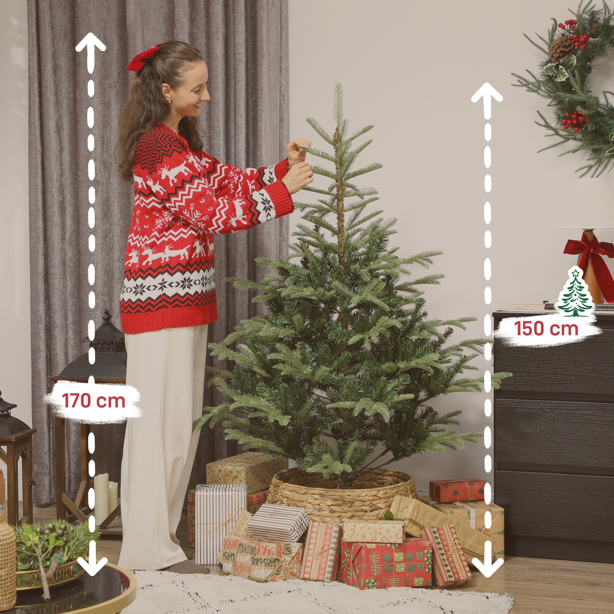 Una mujer con un jersey navideño rojo decora un pequeño árbol de Navidad rodeado de regalos envueltos.