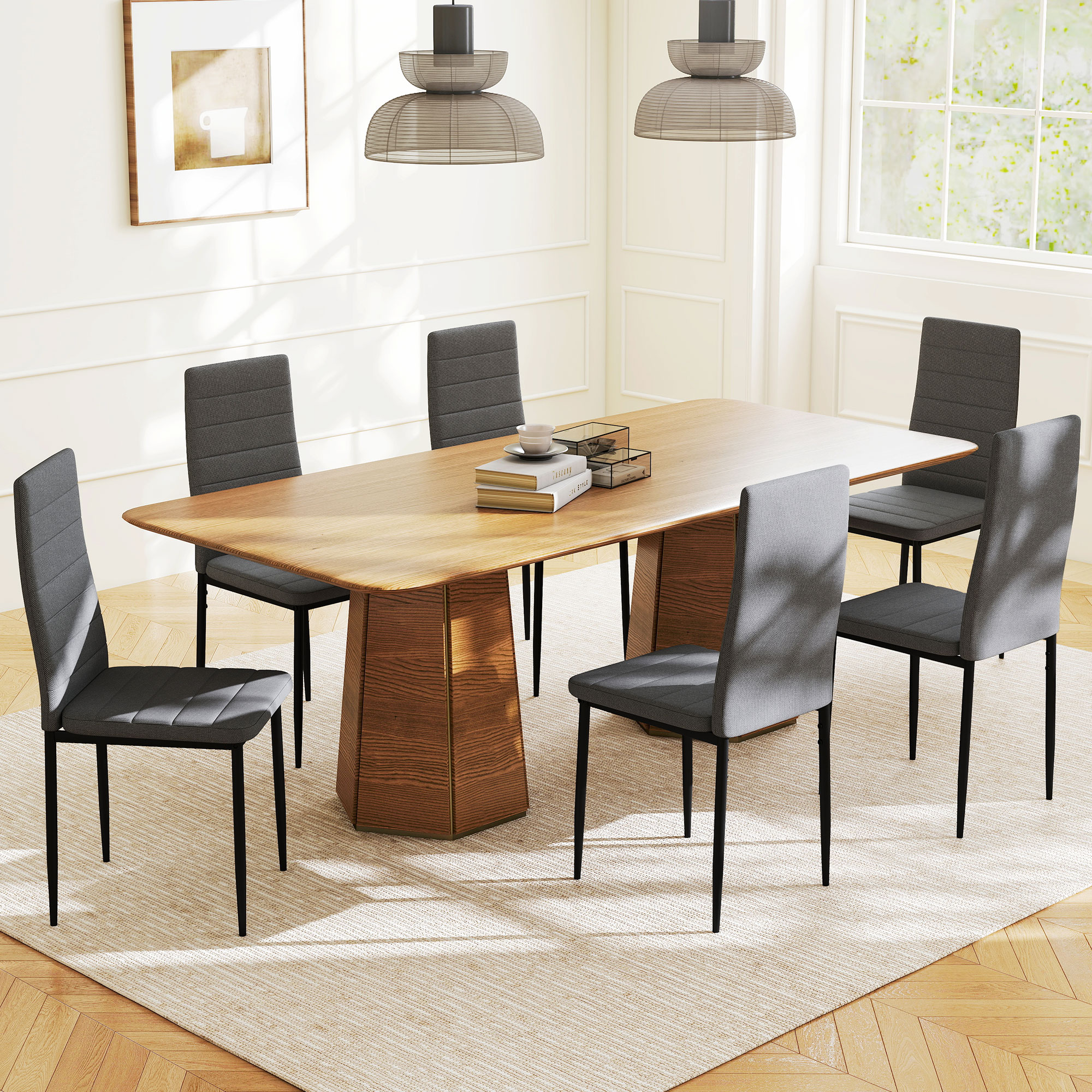Sala da pranzo con tavolo in legno, sei sedie grigie, tappeto, due lampade a sospensione e quadro.